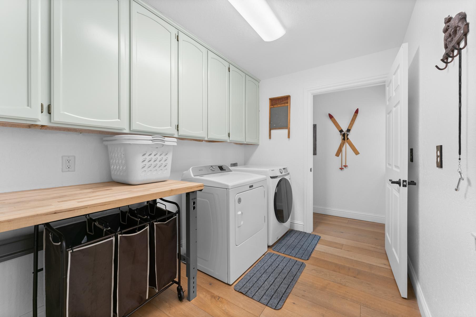 Laundry room in a Truckee vacation rental with mint green cabinets, washer, dryer, and a wooden countertop.