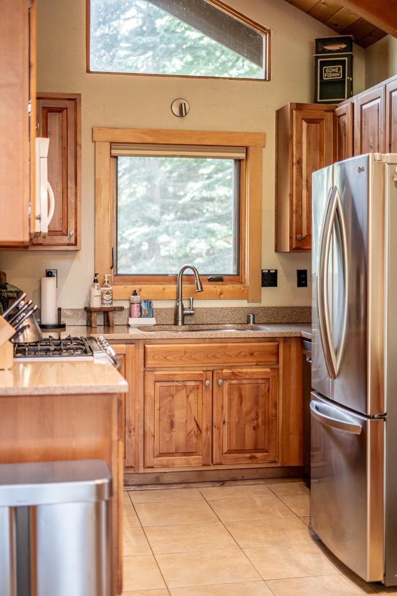 Wooden kitchen with stainless steel appliances in a Truckee vacation rental, featuring a sink and gas stove.