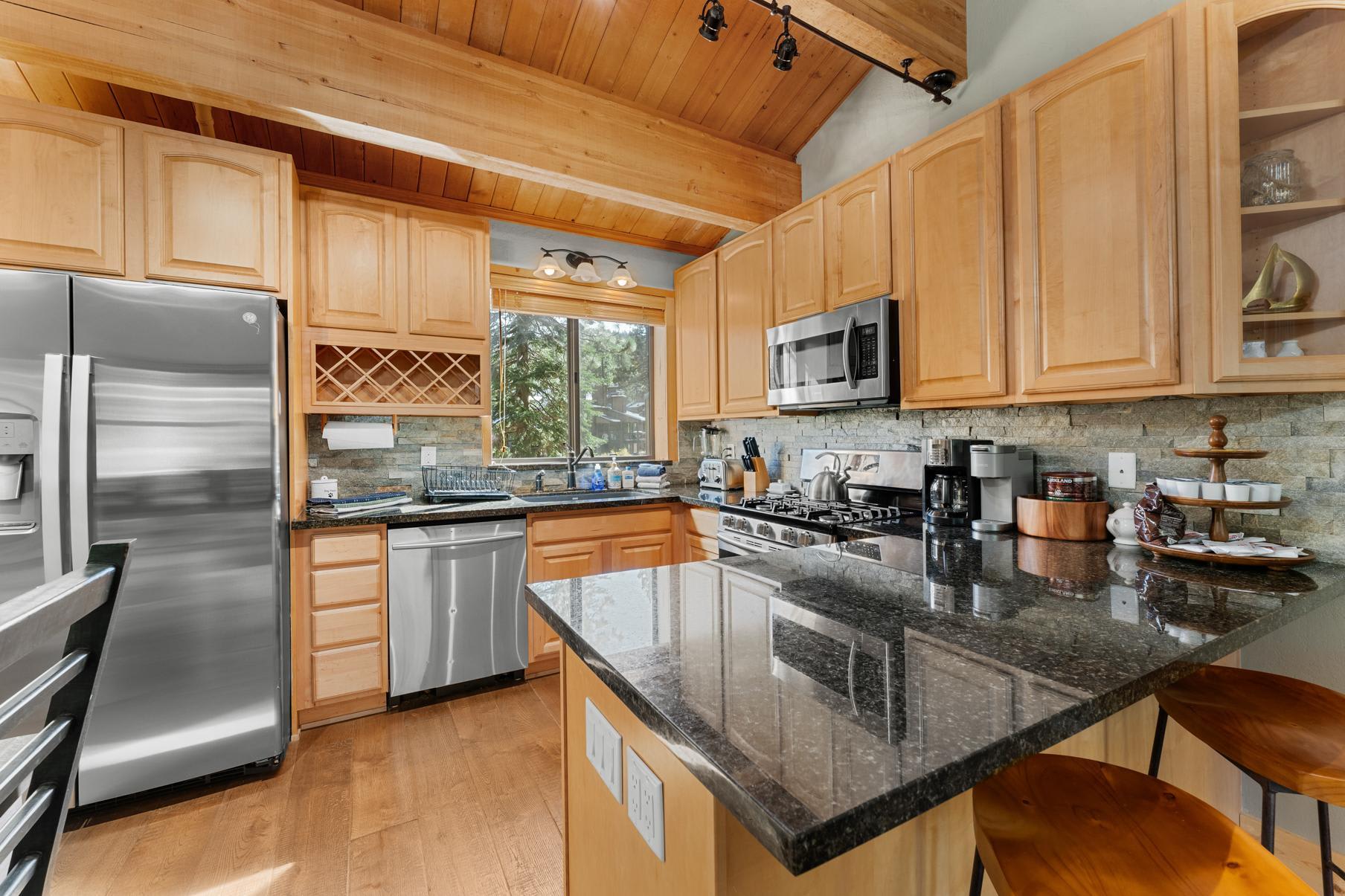 Modern kitchen in a Truckee vacation rental, featuring wooden cabinets, stainless steel appliances, and granite countertops.