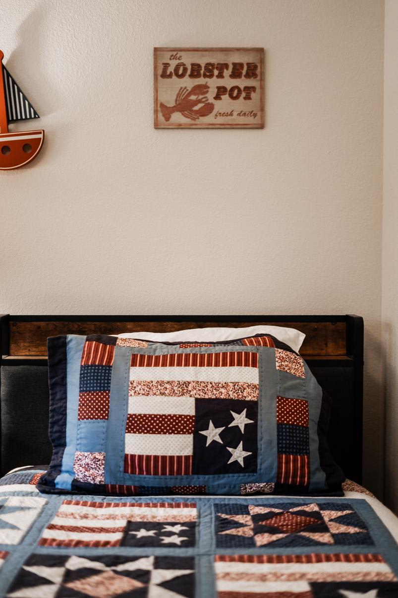 Cozy bedroom in a Truckee vacation rental with a nautical theme quilt and wall decor.