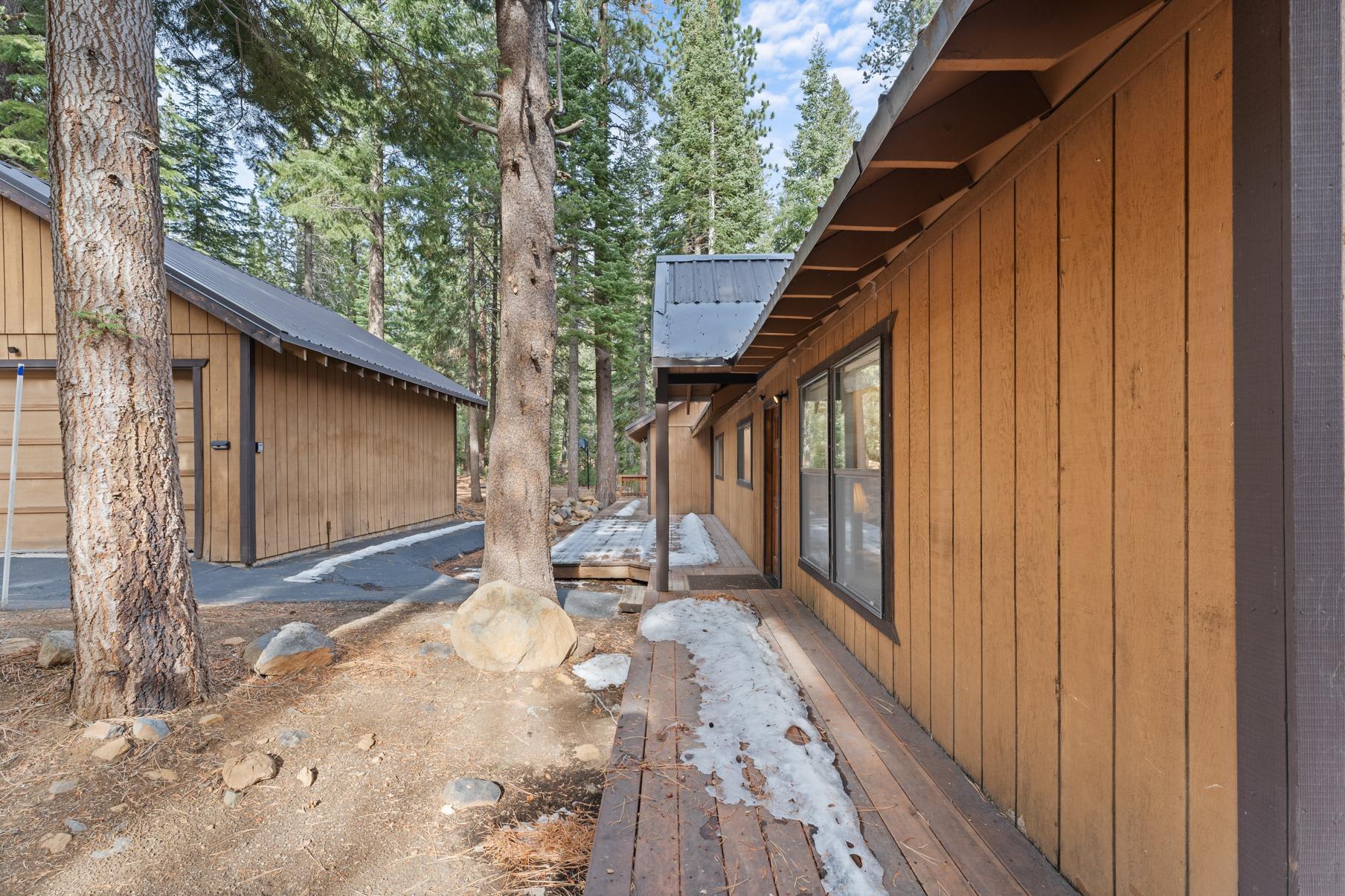 Wooden cabin surrounded by tall trees, a scenic vacation rental in Truckee with light snow on the ground.