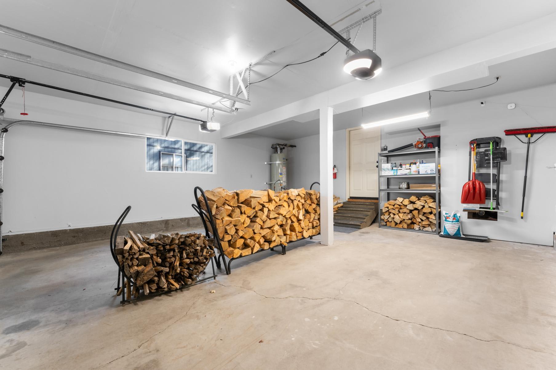 Garage in Truckee vacation rental with firewood stacks, shelves, tools, and a shovel.