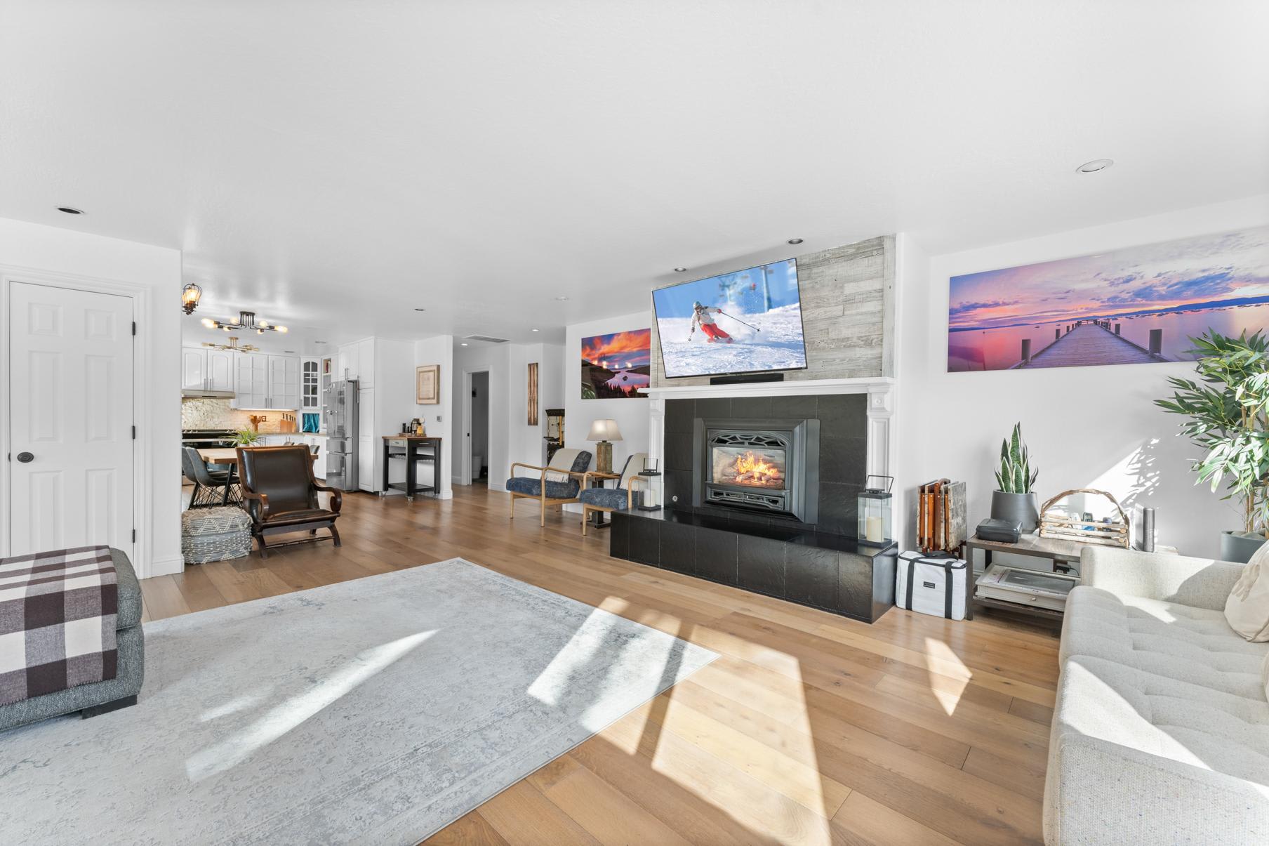 Bright living room in a Truckee vacation rental with a cozy fireplace, modern decor, and a kitchen in the background.