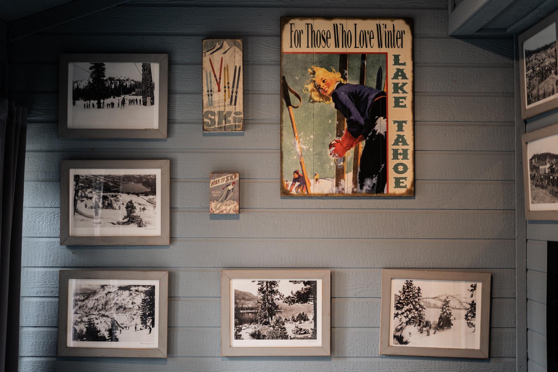 Vintage ski-themed decor on a blue wall in a Truckee vacation rental, featuring Lake Tahoe posters and framed photos.