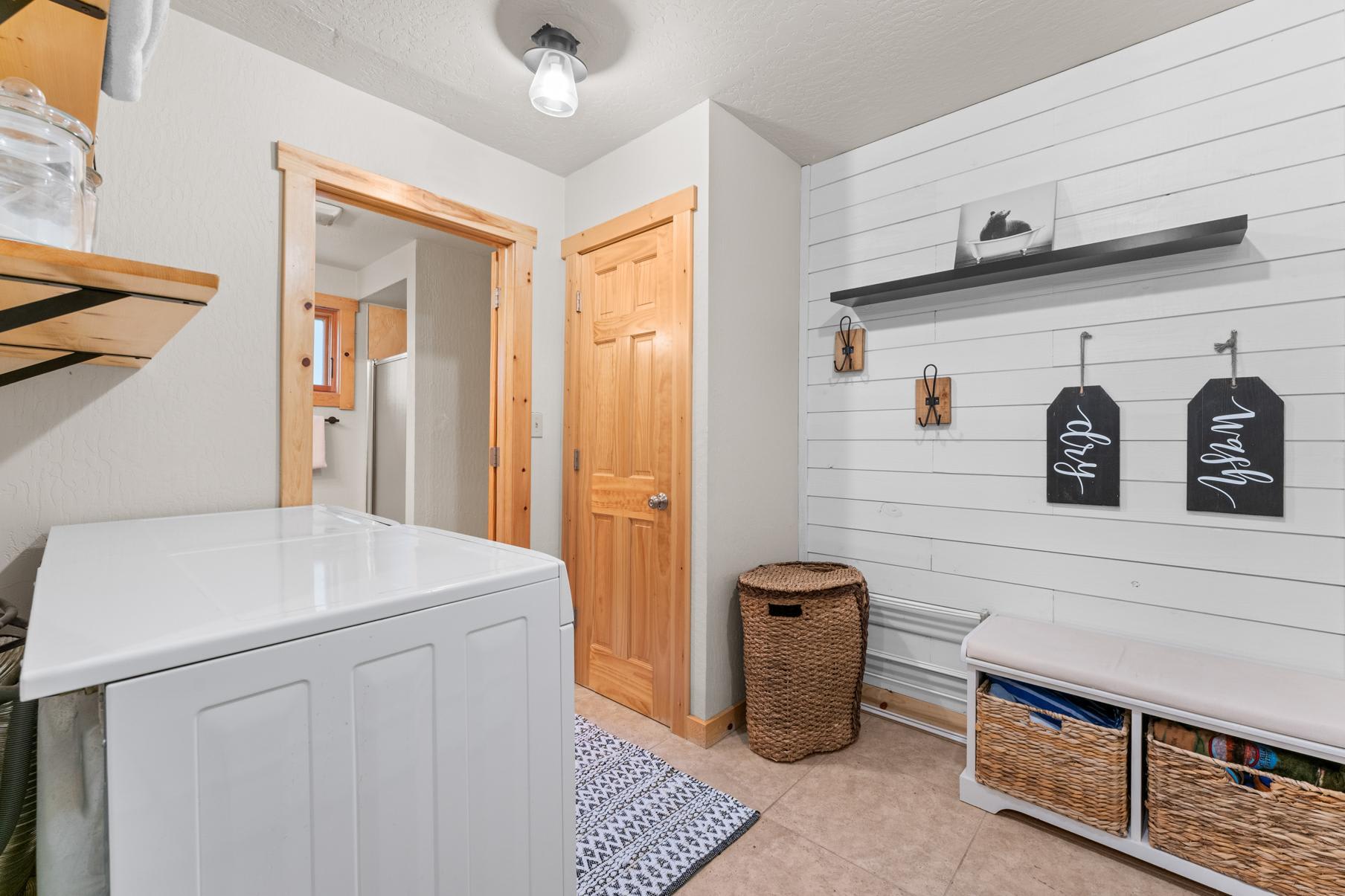 Laundry room in a Truckee vacation rental with wooden accents, a washer, shelves, and woven storage baskets.