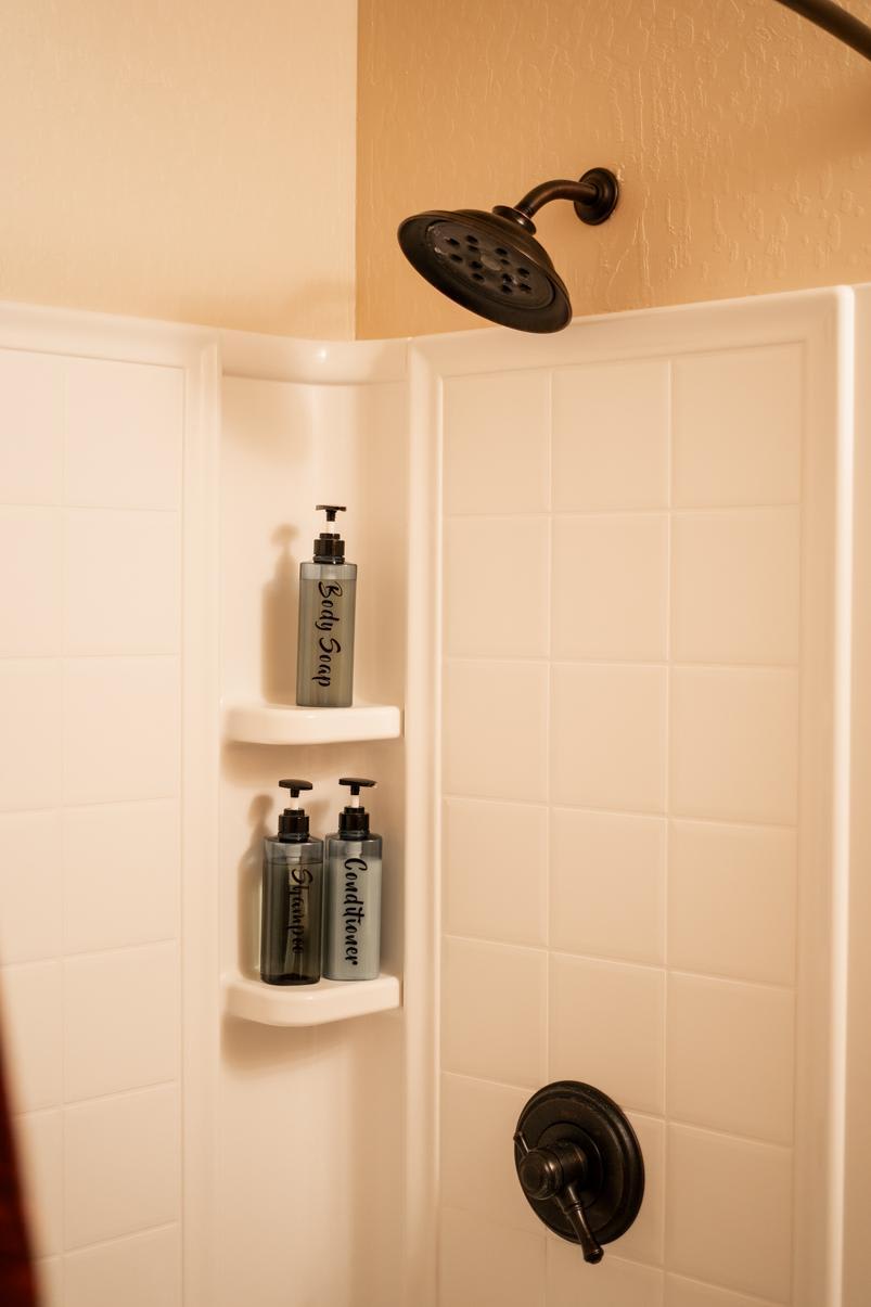 Shower area in a Truckee vacation rental with shampoo, conditioner, and body soap bottles on a shelf.