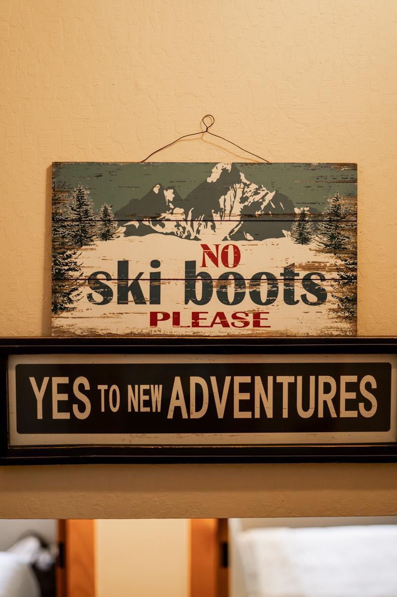 Vintage signs in a Truckee vacation rental say “No Ski Boots Please” and “Yes to New Adventures,” adding a cozy touch.