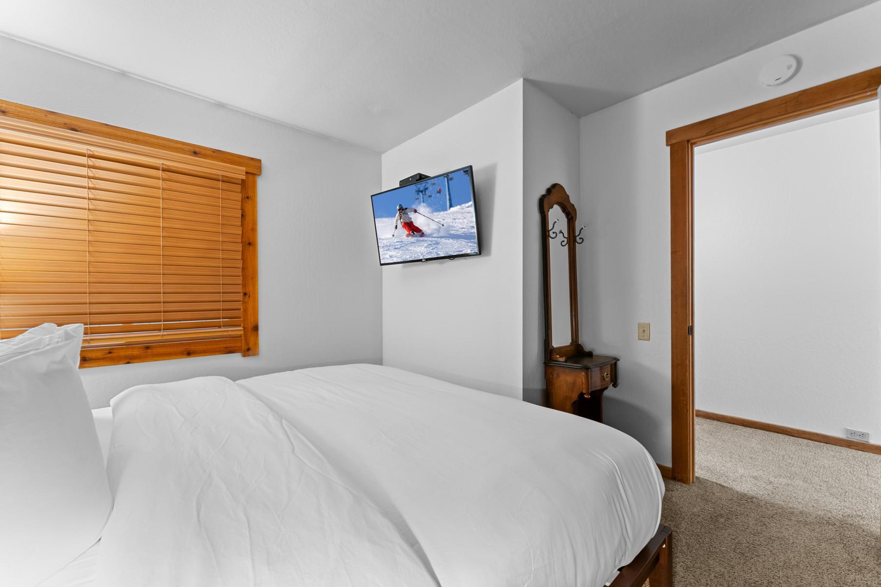 Cozy bedroom with a TV showing skiing, located in a Truckee vacation rental.