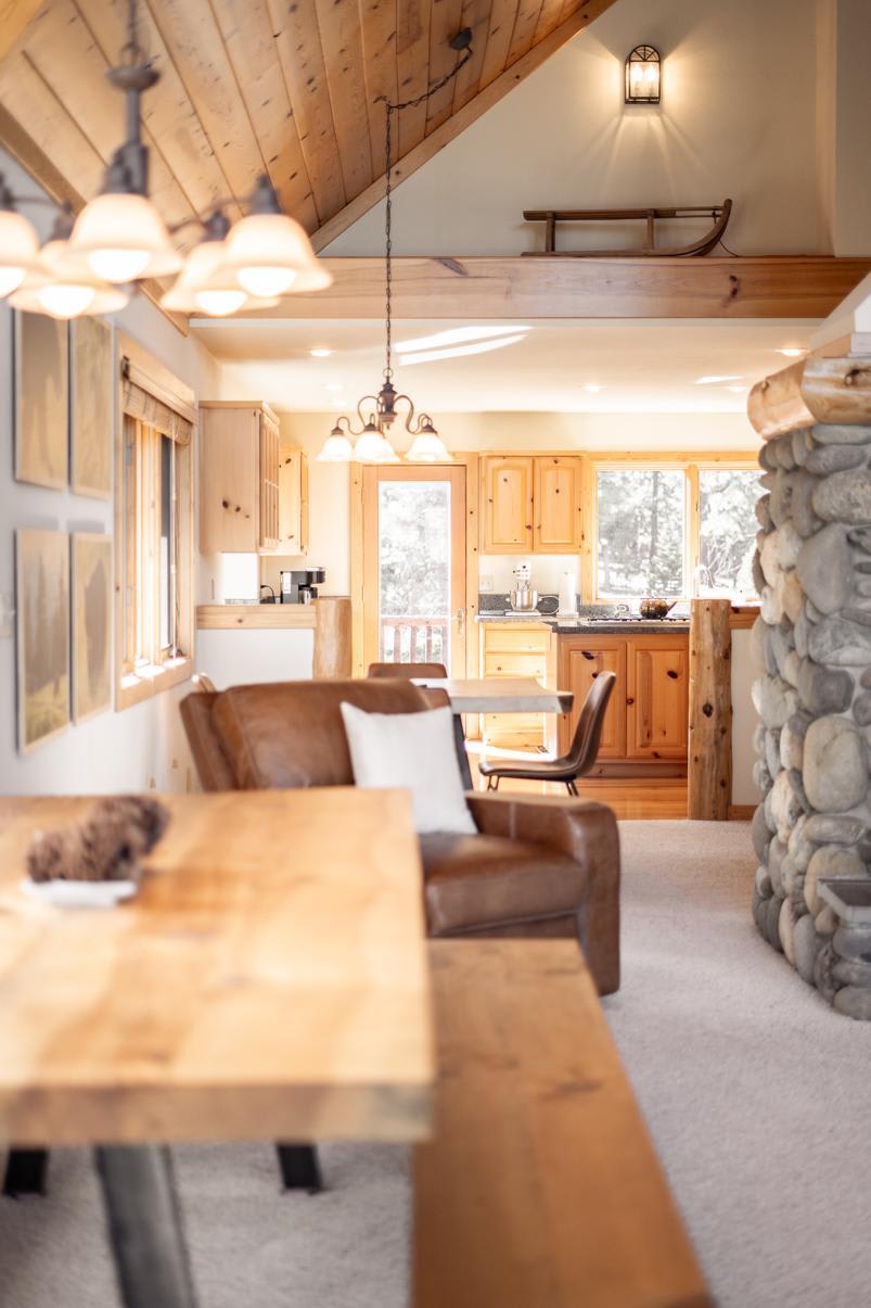 Rustic Truckee vacation rental with wood and stone interiors, featuring a cozy seating area and kitchen in cabin style.