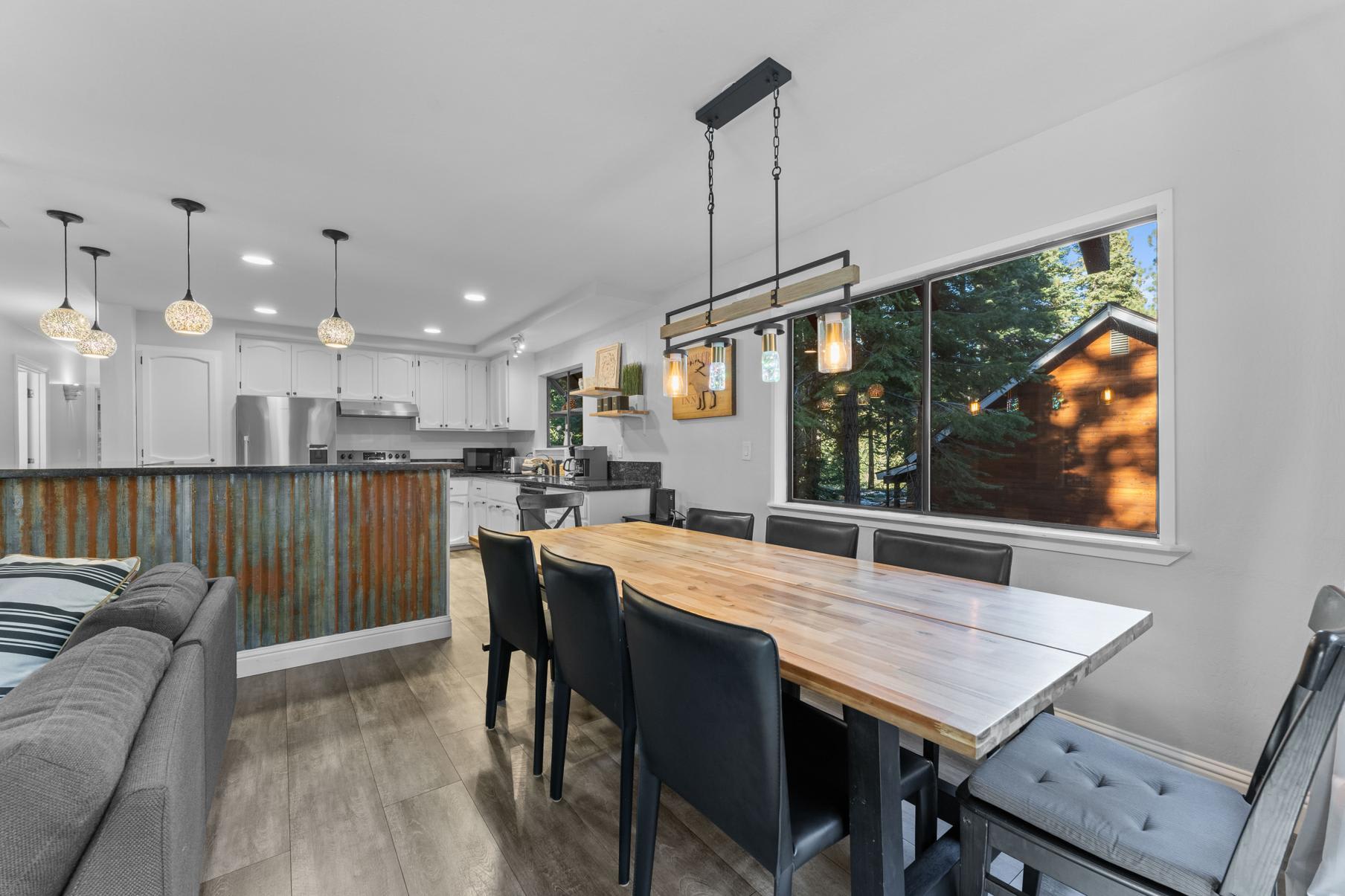 Modern kitchen and dining area in Tahoe Vista vacation rental with forest view through large windows.