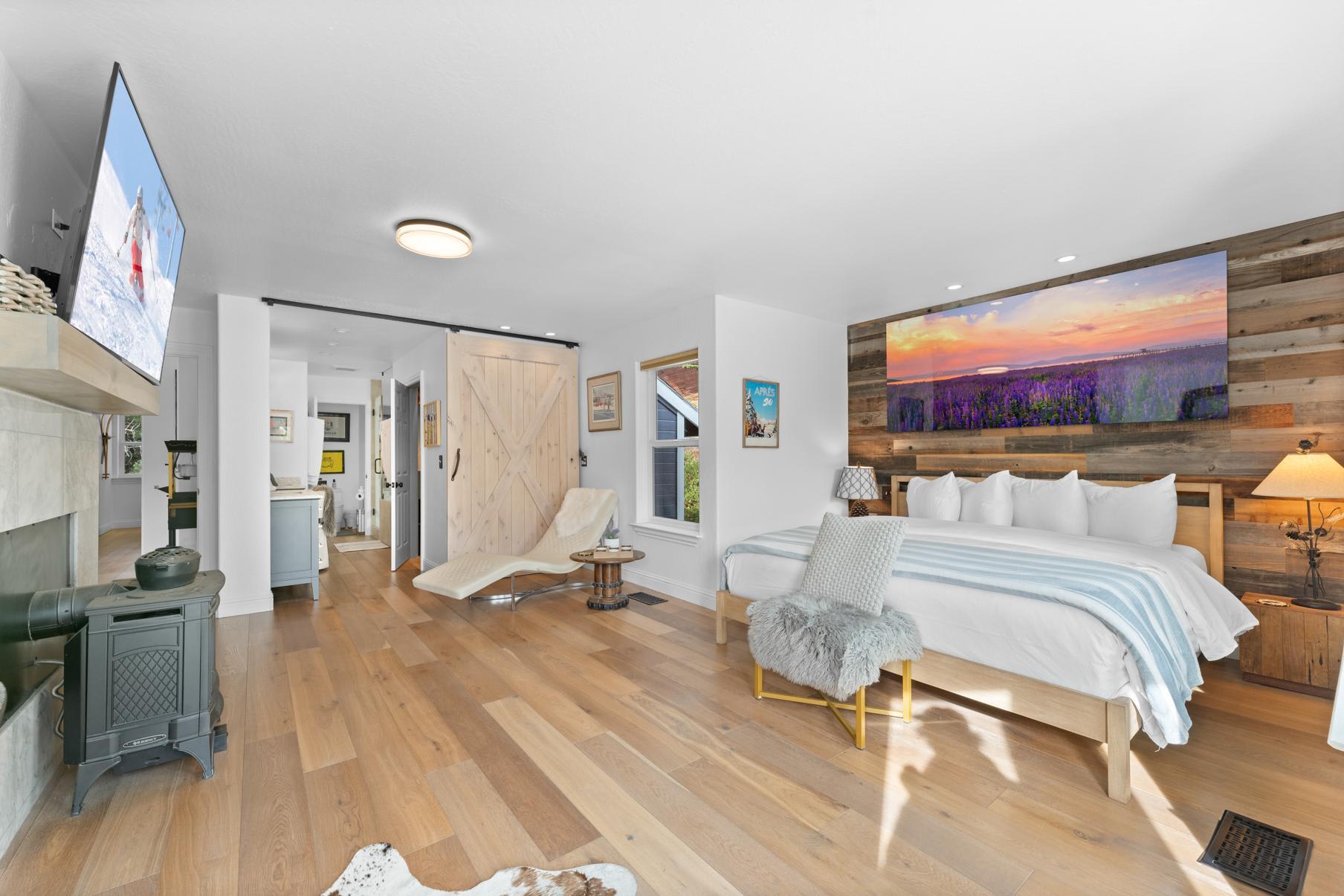 Modern bedroom in a Truckee vacation rental, with wood floors, cozy seating, and a large bed under scenic wall art.