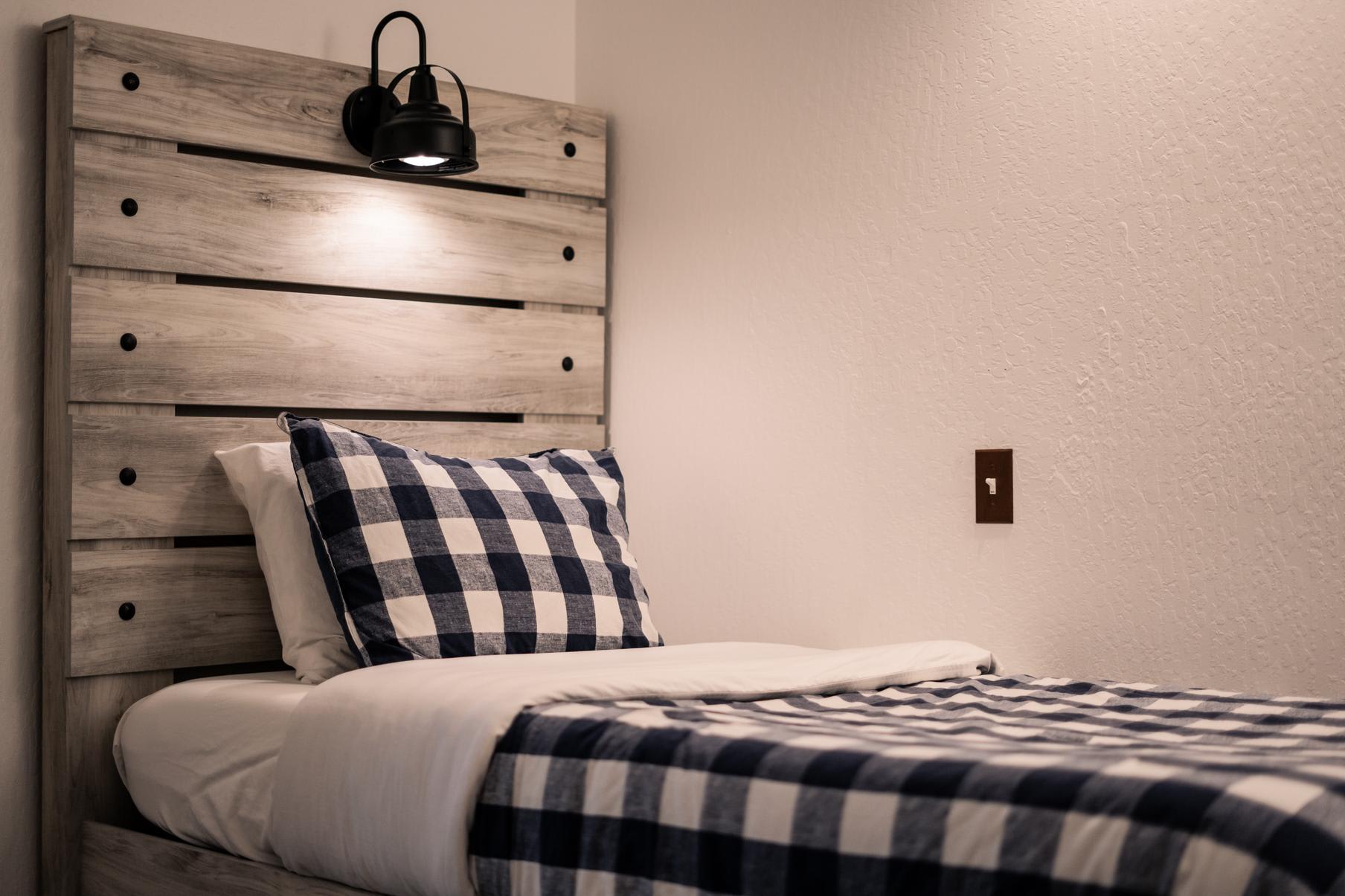 Cozy bedroom with plaid bedding in a Truckee vacation rental featuring a wooden headboard and soft lighting.