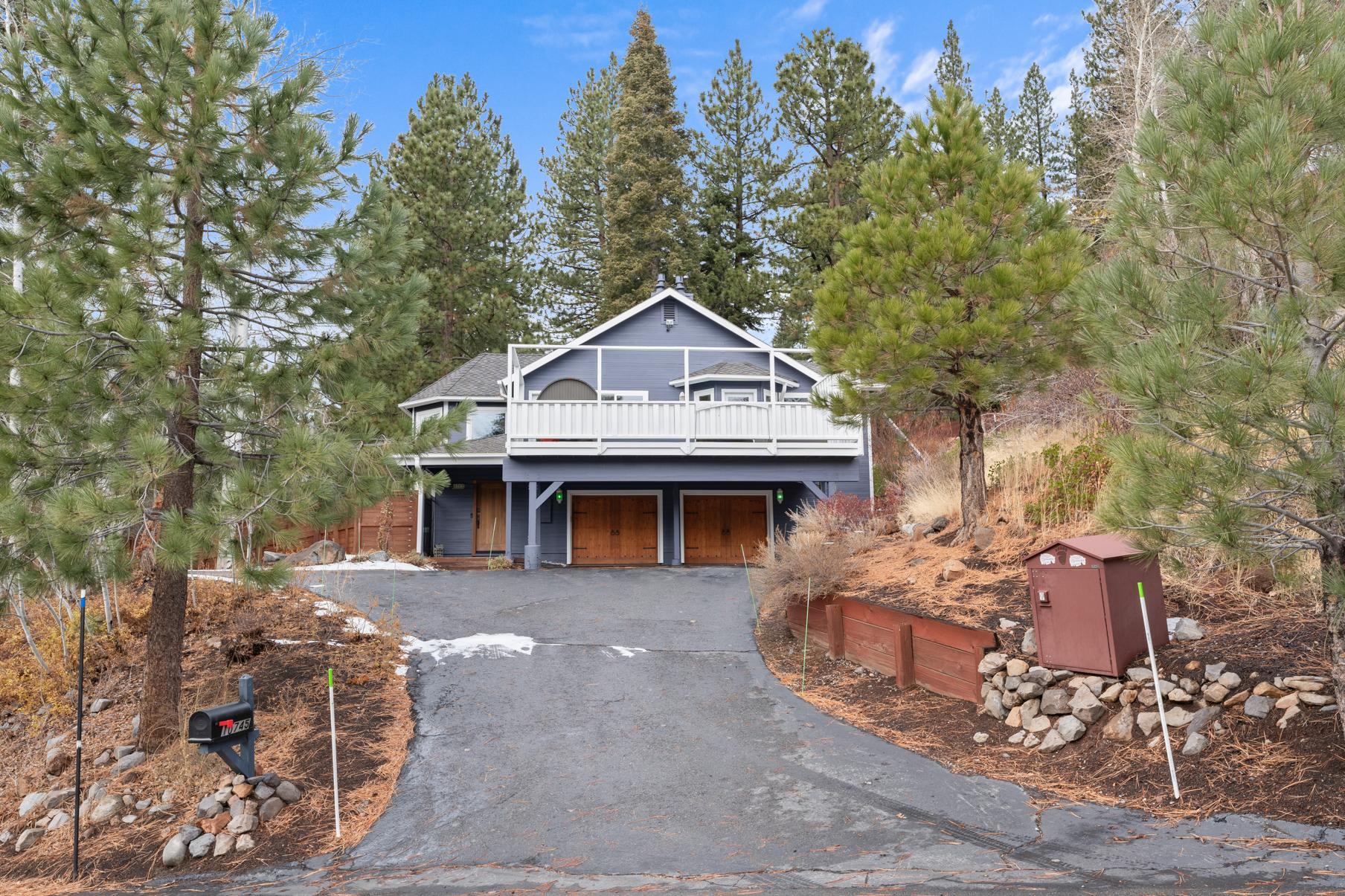 A charming cabin-style vacation rental in Truckee, nestled among tall trees with a wide driveway and wooden accents.