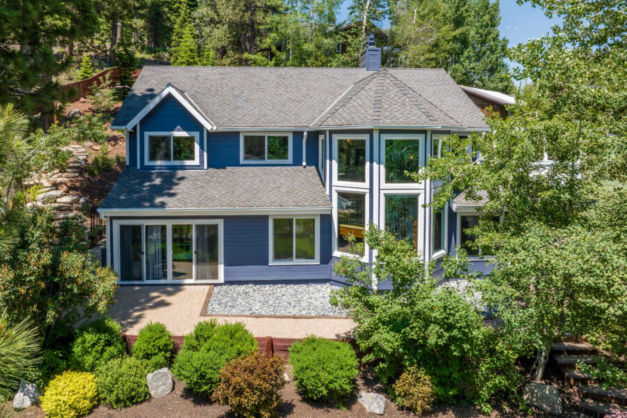 Blue vacation rental house in Truckee surrounded by lush greenery and sunny skies.