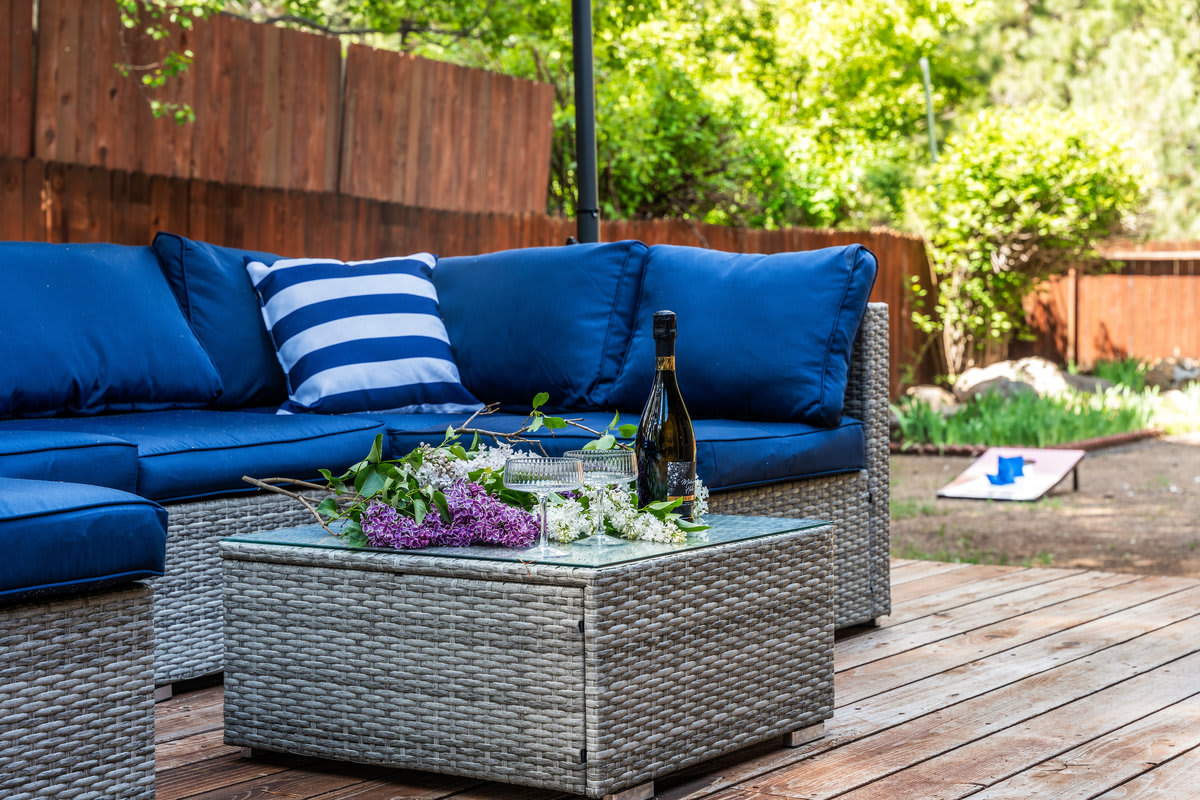 Outdoor seating area at a Truckee vacation rental, with blue cushions and a table set with flowers and wine.