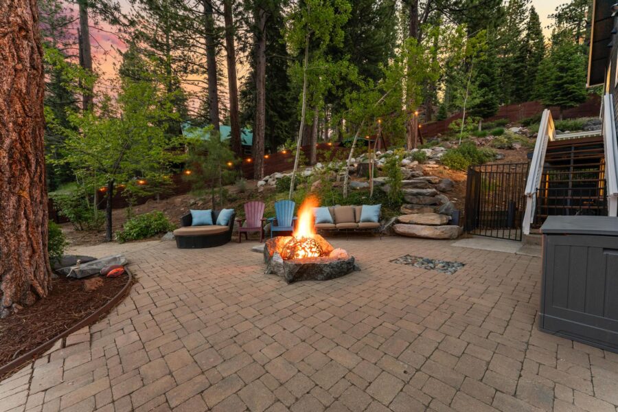 Cozy backyard with fire pit and seating in Truckee vacation rental, surrounded by trees at sunset.