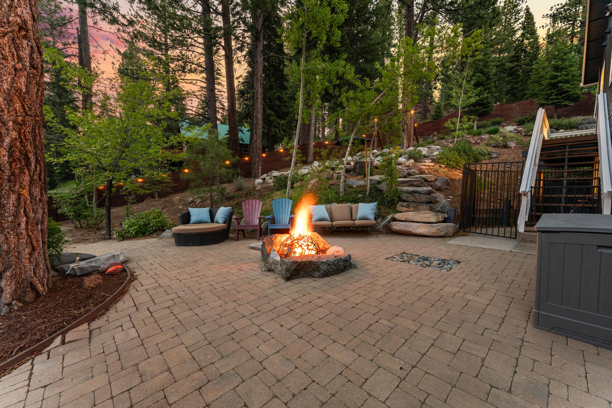 Cozy backyard with fire pit and seating in Truckee vacation rental, surrounded by trees at sunset.