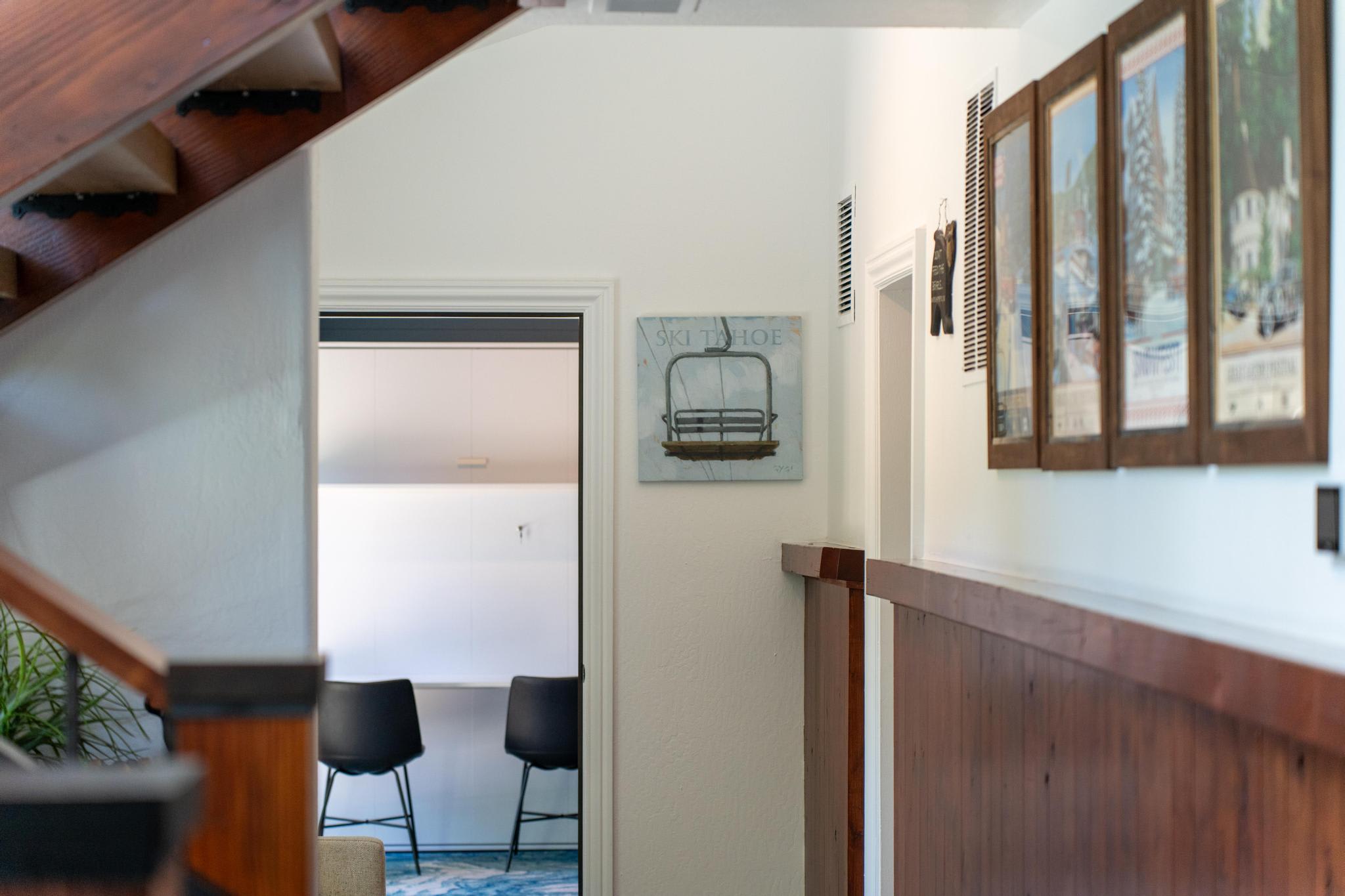 Interior view of a Truckee vacation rental with wooden staircase, Ski Tahoe artwork, and a cozy seating area.