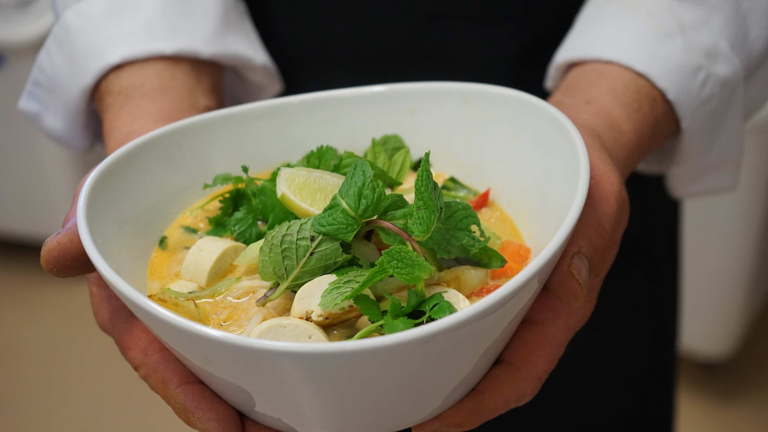 Person holding a bowl of fresh herb and lime-topped soup in a Truckee vacation rental kitchen.