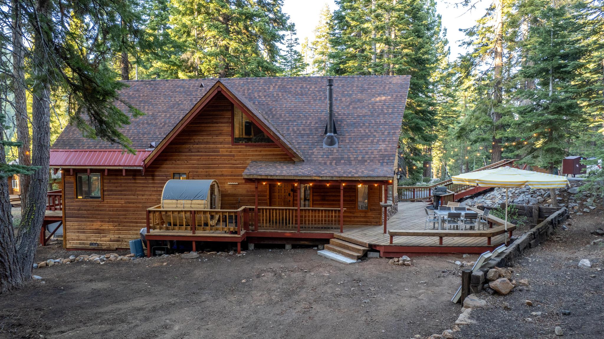 Rustic cabin-style vacation rental nestled in wooded Tahoe Vista, featuring a spacious deck and cozy outdoor seating area.