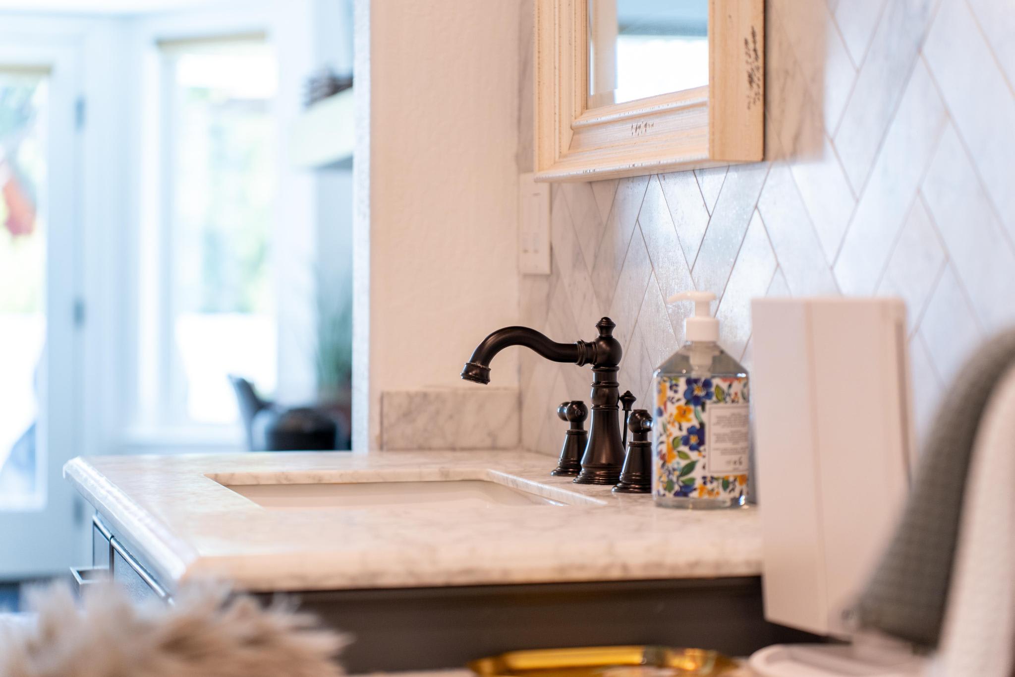 Elegant bathroom sink with marble countertop in Truckee vacation rental, featuring decorative soap dispenser.