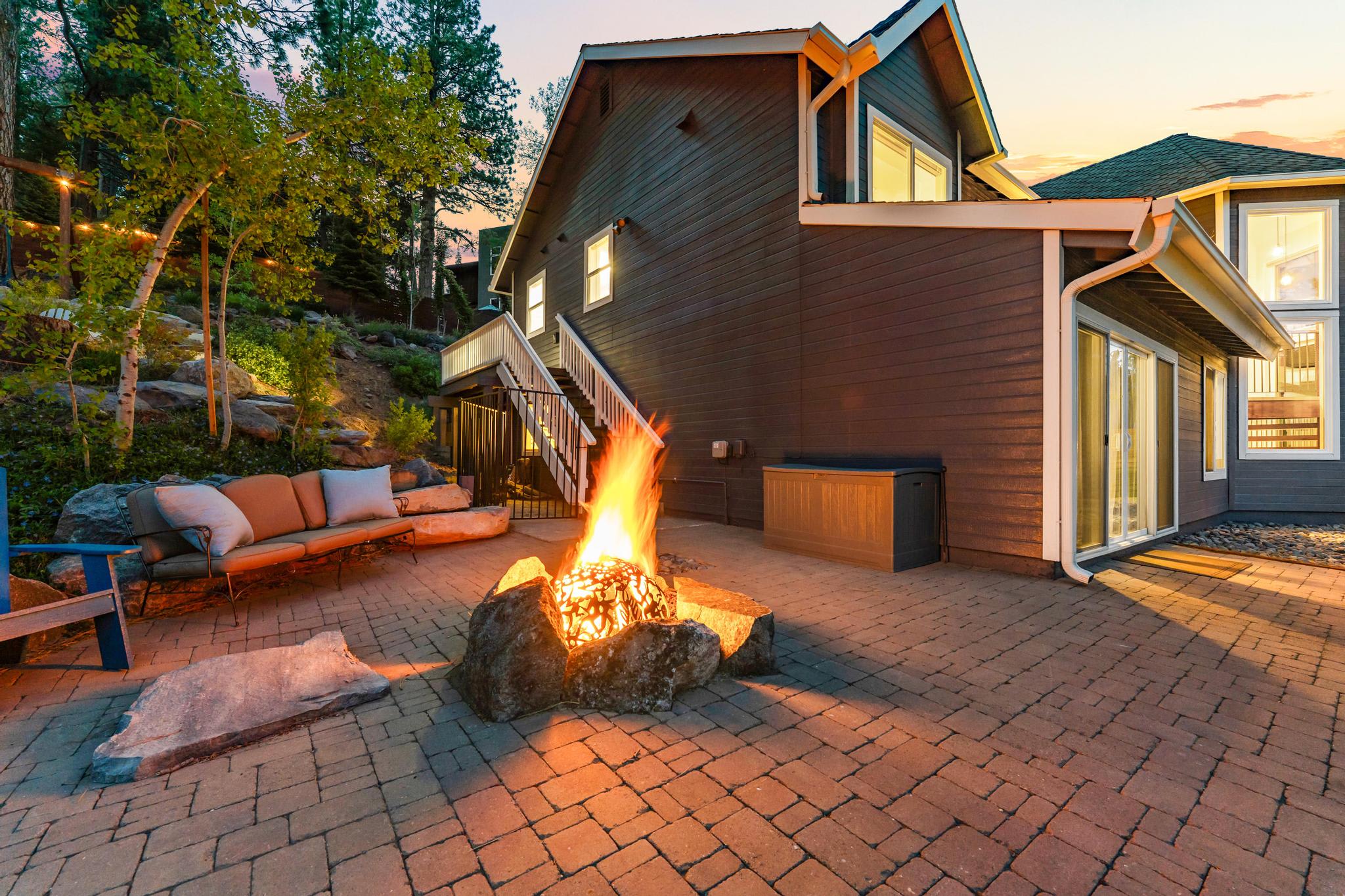 Cozy Truckee vacation rental with a fire pit on a patio, surrounded by trees and a comfortable outdoor seating area.