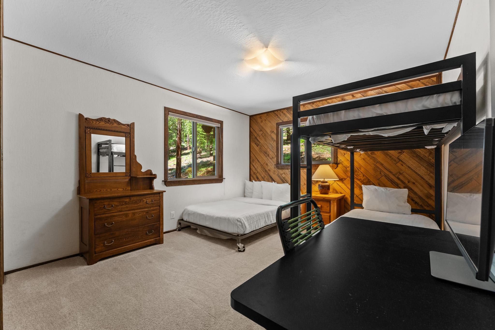 Room in Tahoe Vista vacation rental with bunk bed, double bed, wooden dresser, and forest view windows.