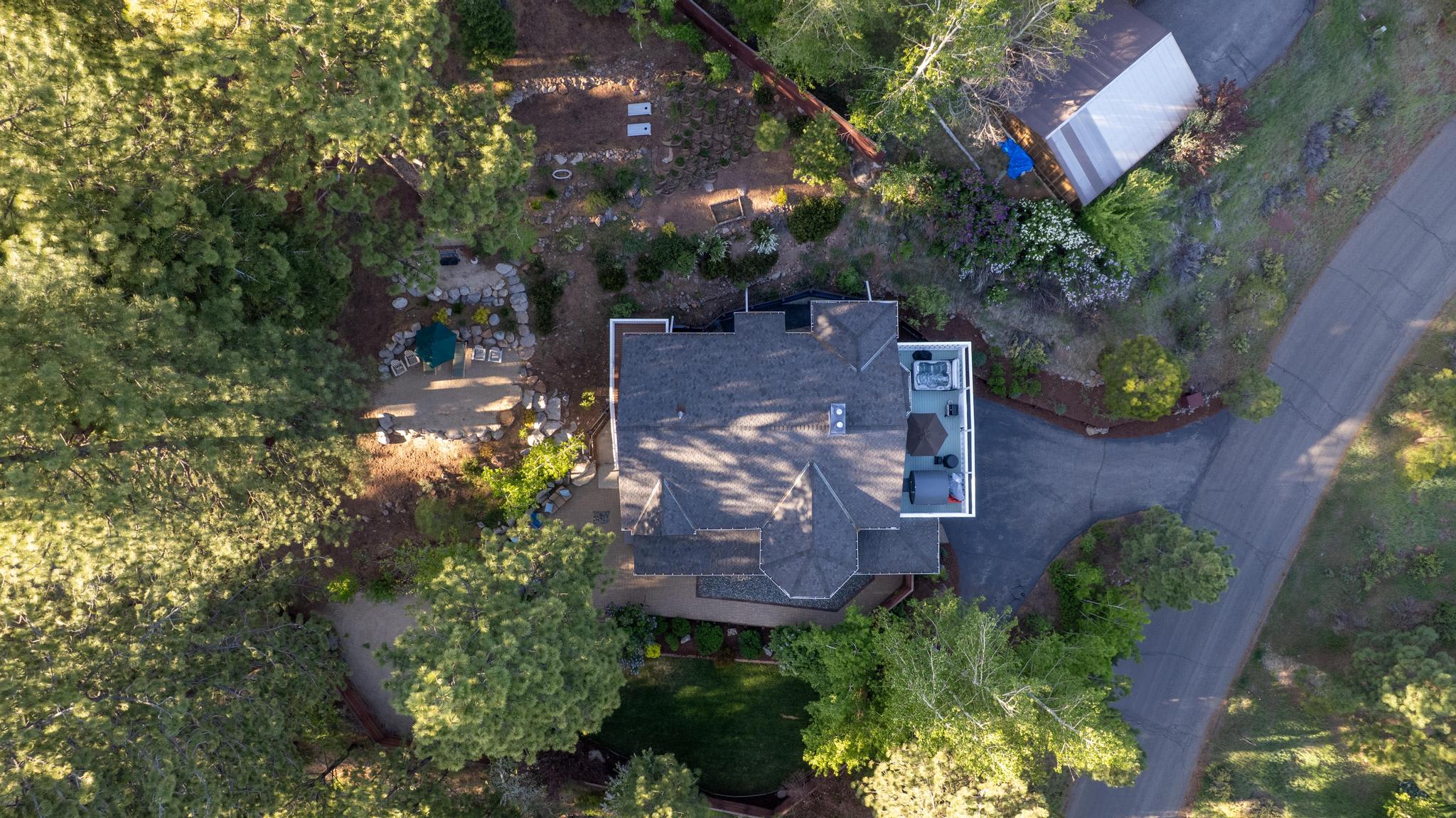 Aerial view of a vacation rental surrounded by trees in Truckee, featuring a patio area and driveway.