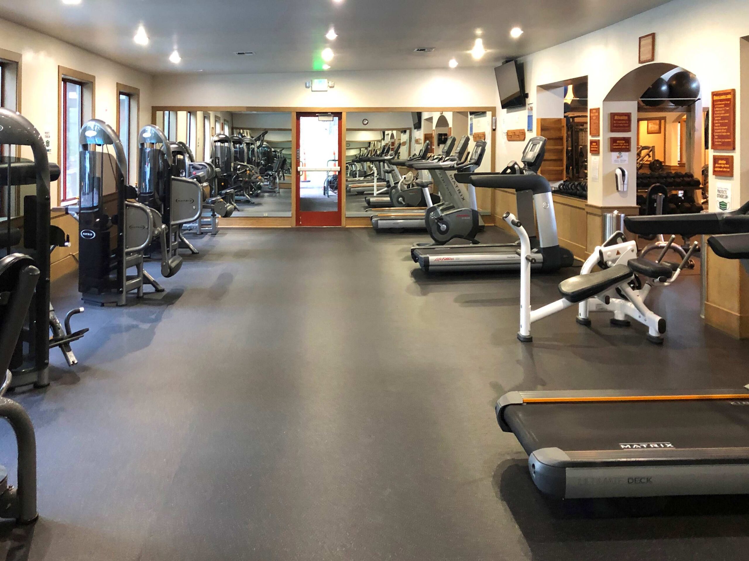Fitness center in Truckee vacation rental with treadmills, weight machines, and mirrors reflecting the bright, spacious room.