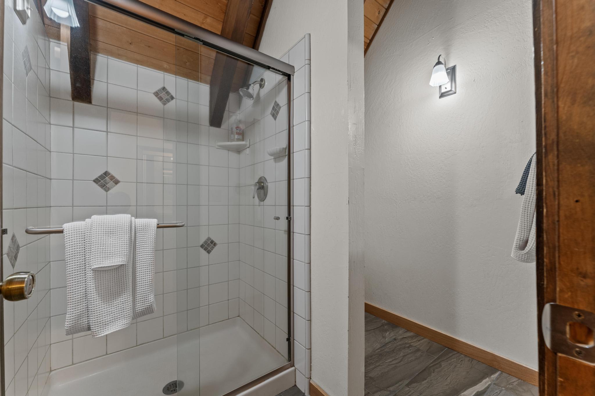 Shower with white tiles and towels in a Tahoe Vista vacation rental bathroom.