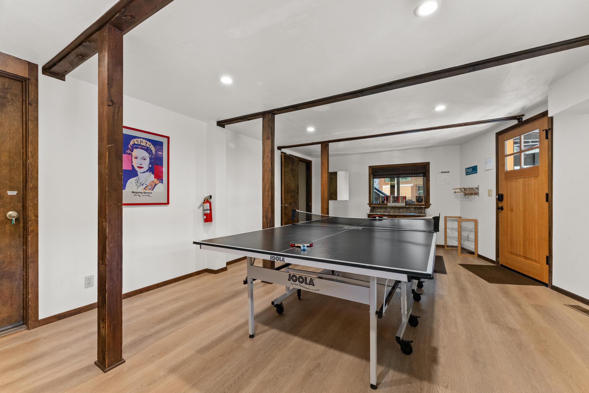 Ping pong table in a Tahoe Vista vacation rental with wooden beams and a portrait on the wall.