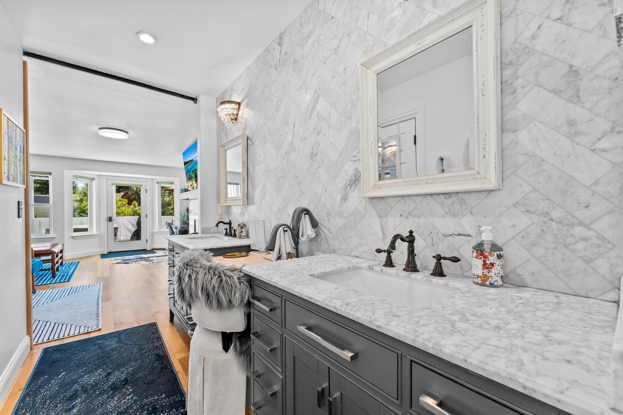 Modern bathroom in a Truckee vacation rental featuring marble countertops and elegant decor, leading to a bright room.