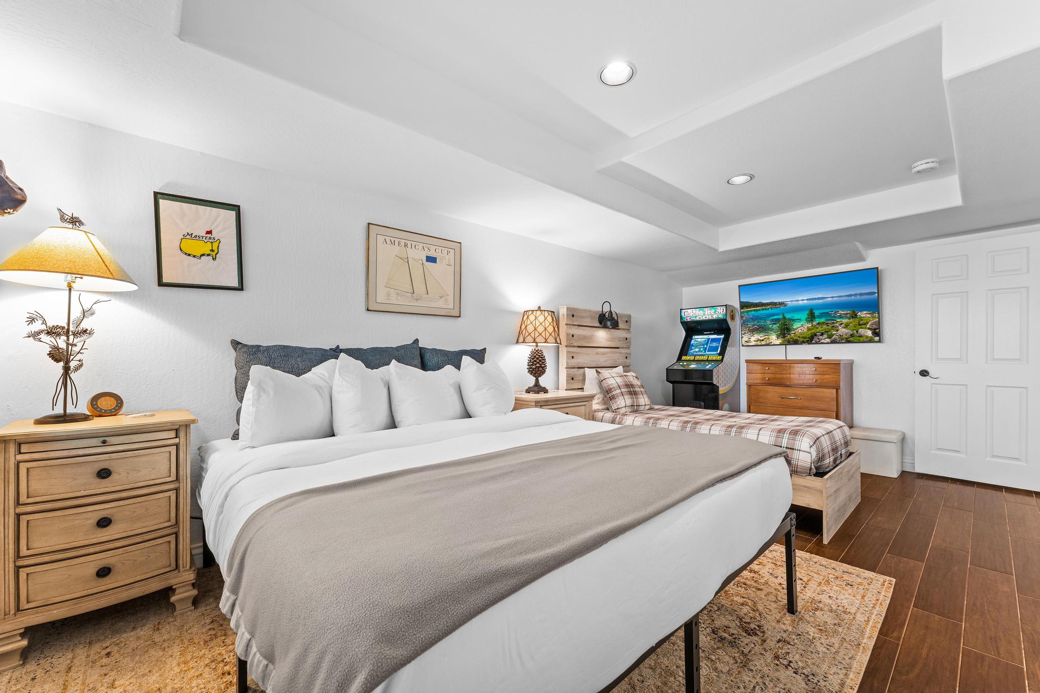 Cozy bedroom in Truckee vacation rental, featuring a king bed, arcade game, TV, and wooden furnishings.