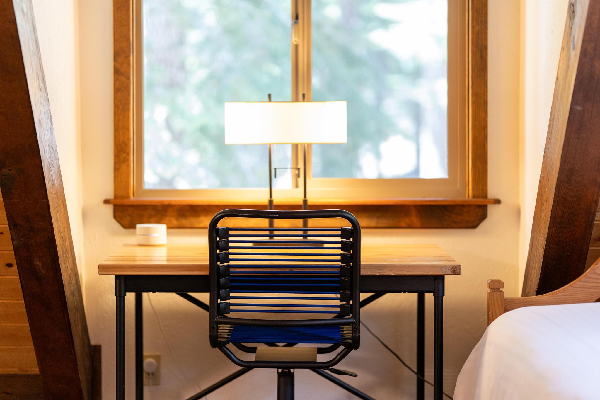Cozy vacation rental workspace in Tahoe Vista featuring a modern desk, chair, and lamp by a window.