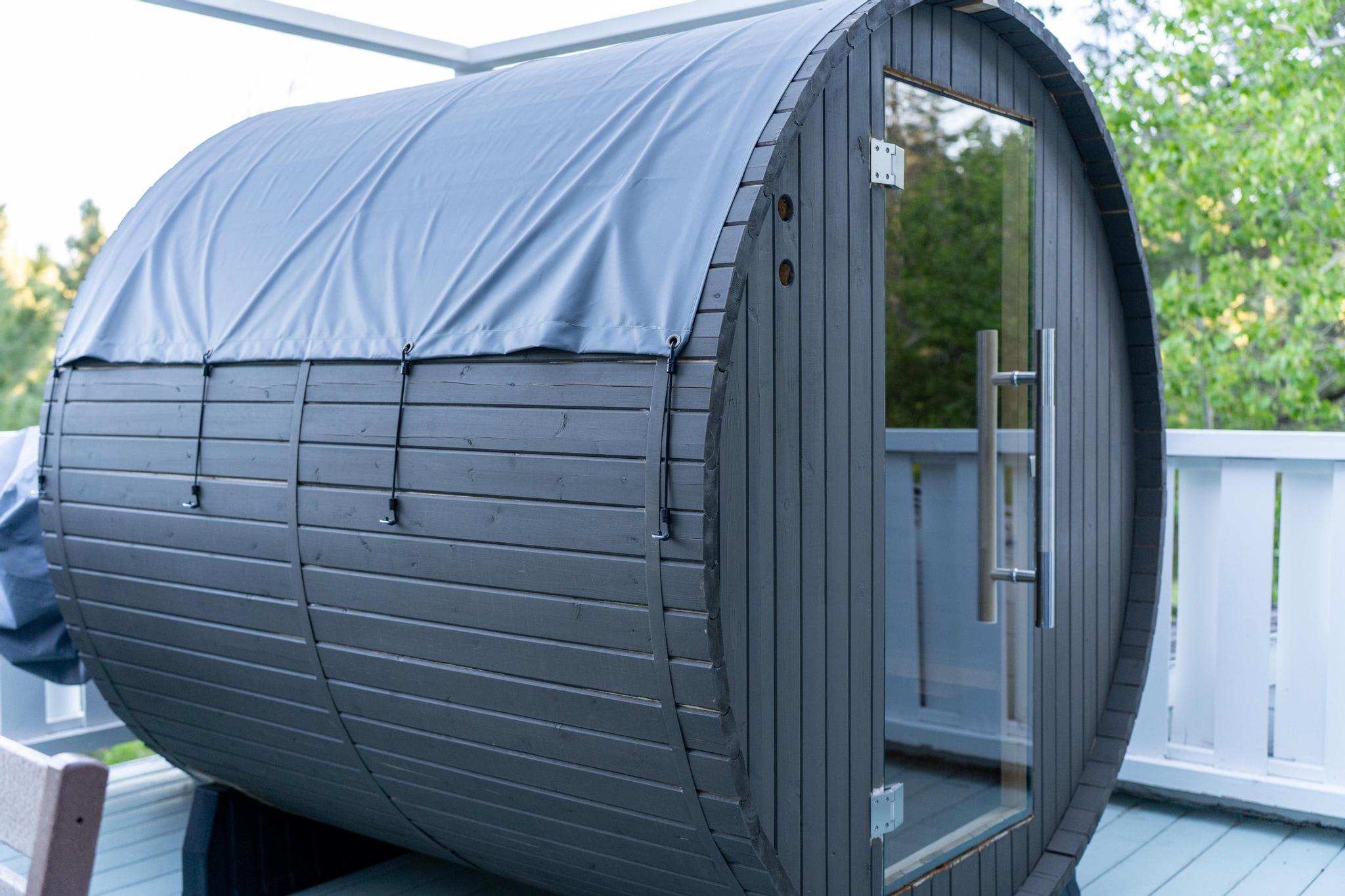 Wooden barrel sauna on the deck of a Truckee vacation rental, surrounded by greenery.