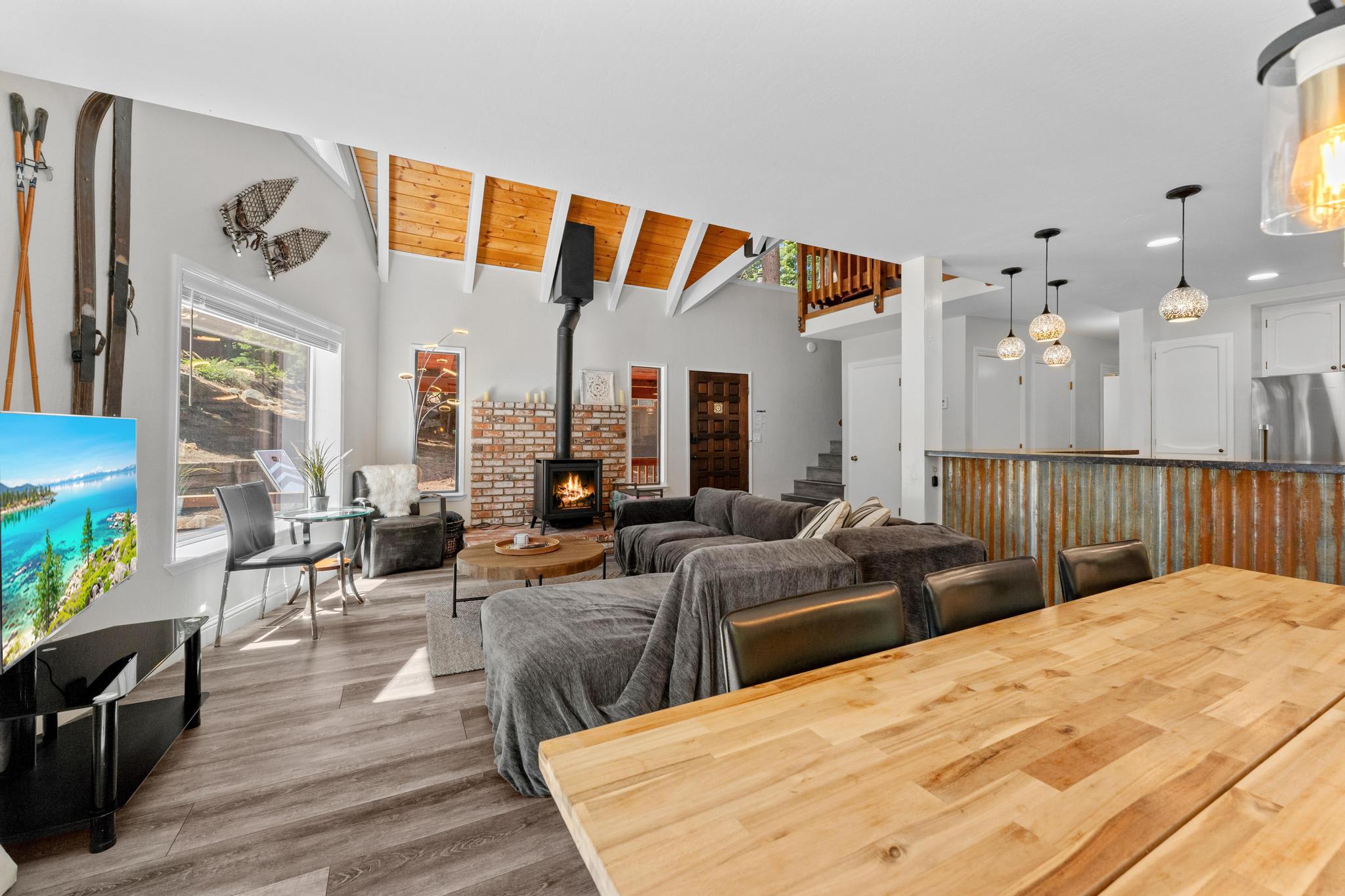 Spacious Tahoe Vista vacation rental living room with cozy sofas, a fireplace, and rustic wood ceiling beams.