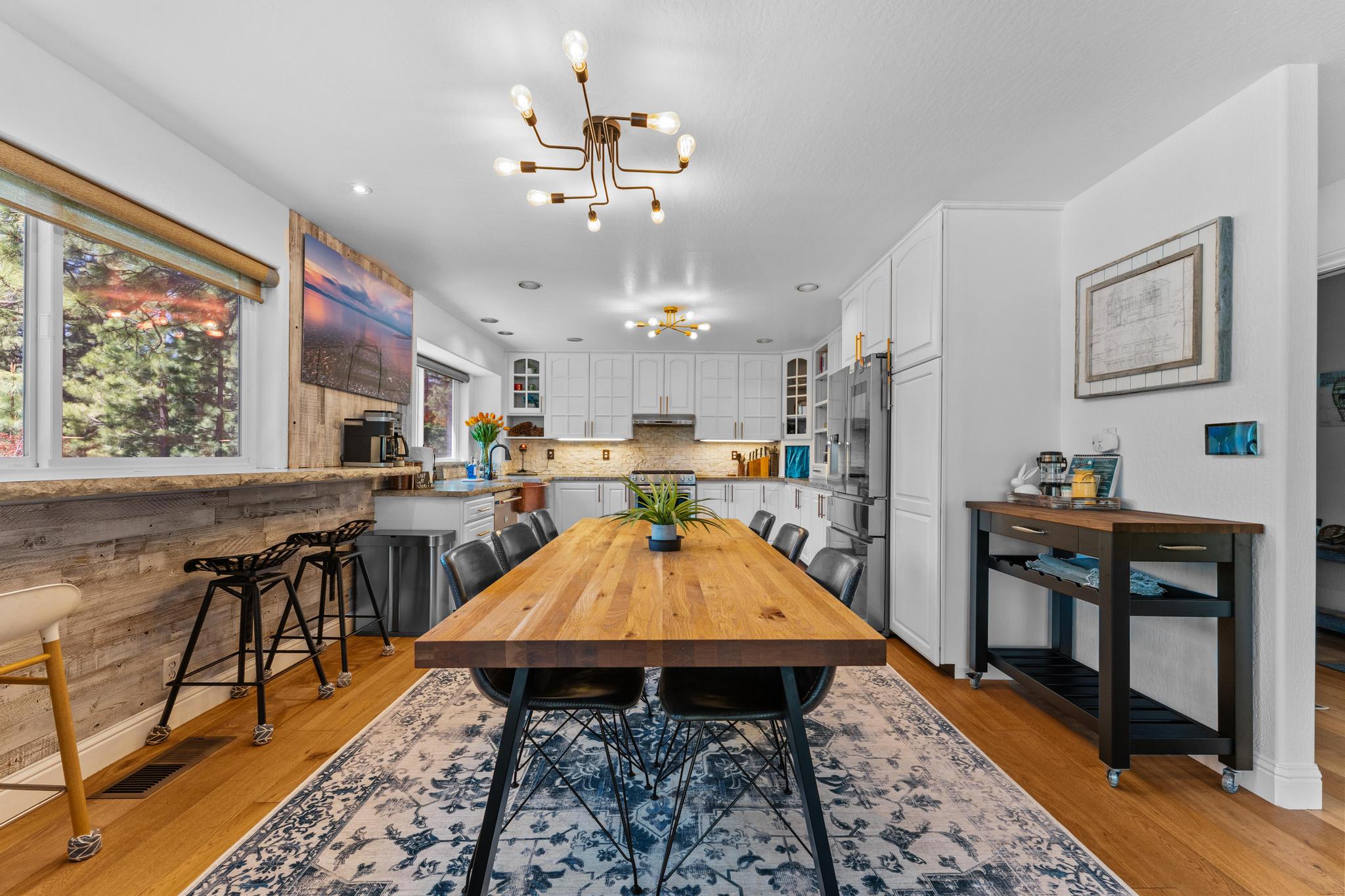 Modern dining area in a Truckee vacation rental, featuring a large wooden table, stylish lighting, and a cozy kitchen.