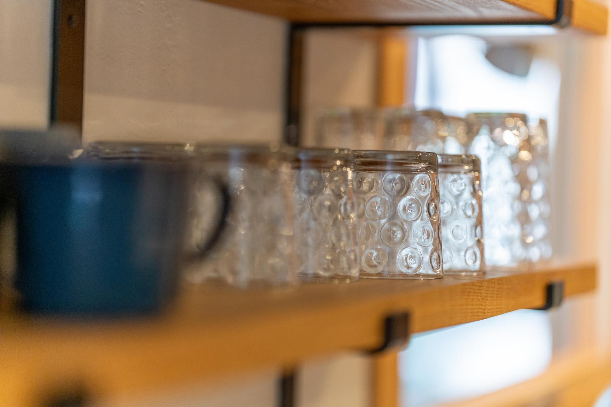 Close-up of glasses and a mug on a wooden shelf in a Tahoe Vista vacation rental kitchen.