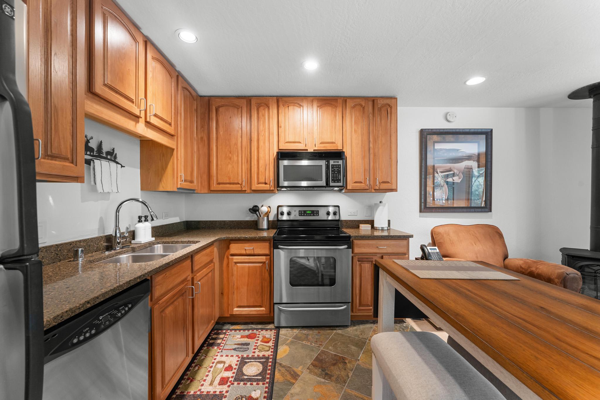 Cozy kitchen area in a Truckee vacation rental with wooden cabinets, stainless steel appliances, and a rustic dining table.