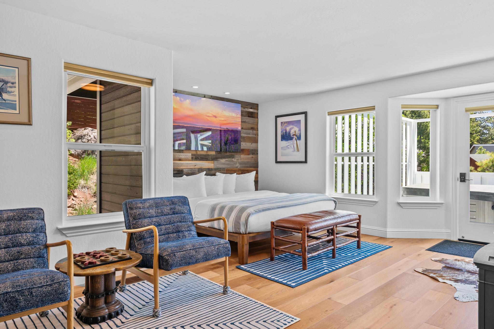Modern bedroom in a Truckee vacation rental, featuring a cozy bed, chairs, large windows, and vibrant wall art.