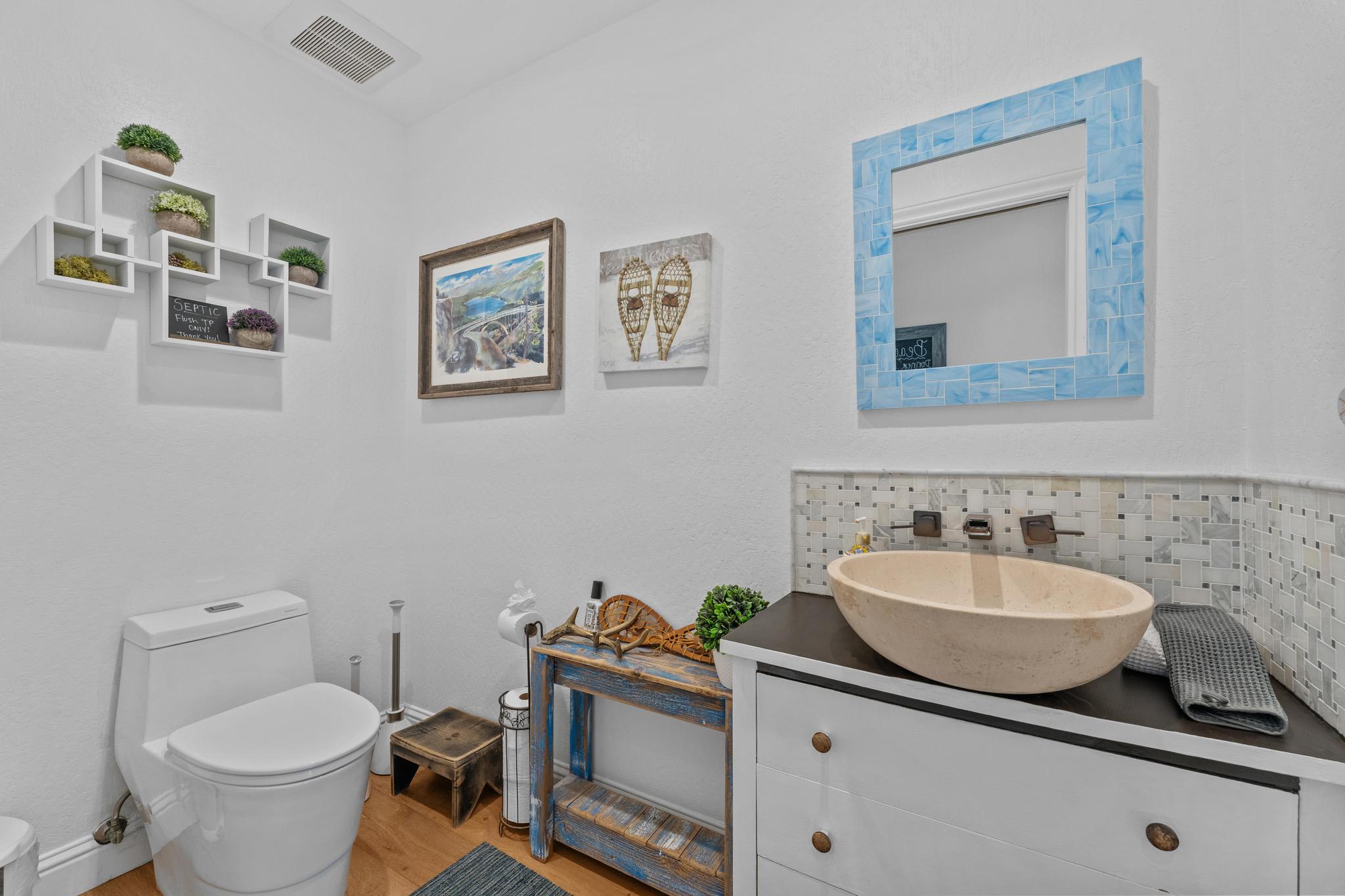 Bathroom in a Truckee vacation rental with modern decor, wooden accents, and blue framed mirror.