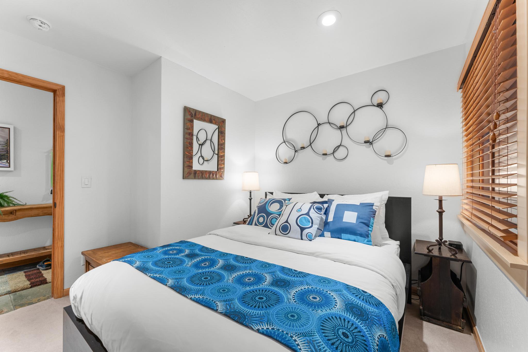 Cozy bedroom in Truckee vacation rental, features modern decor, vibrant blue accents, and warm lighting.