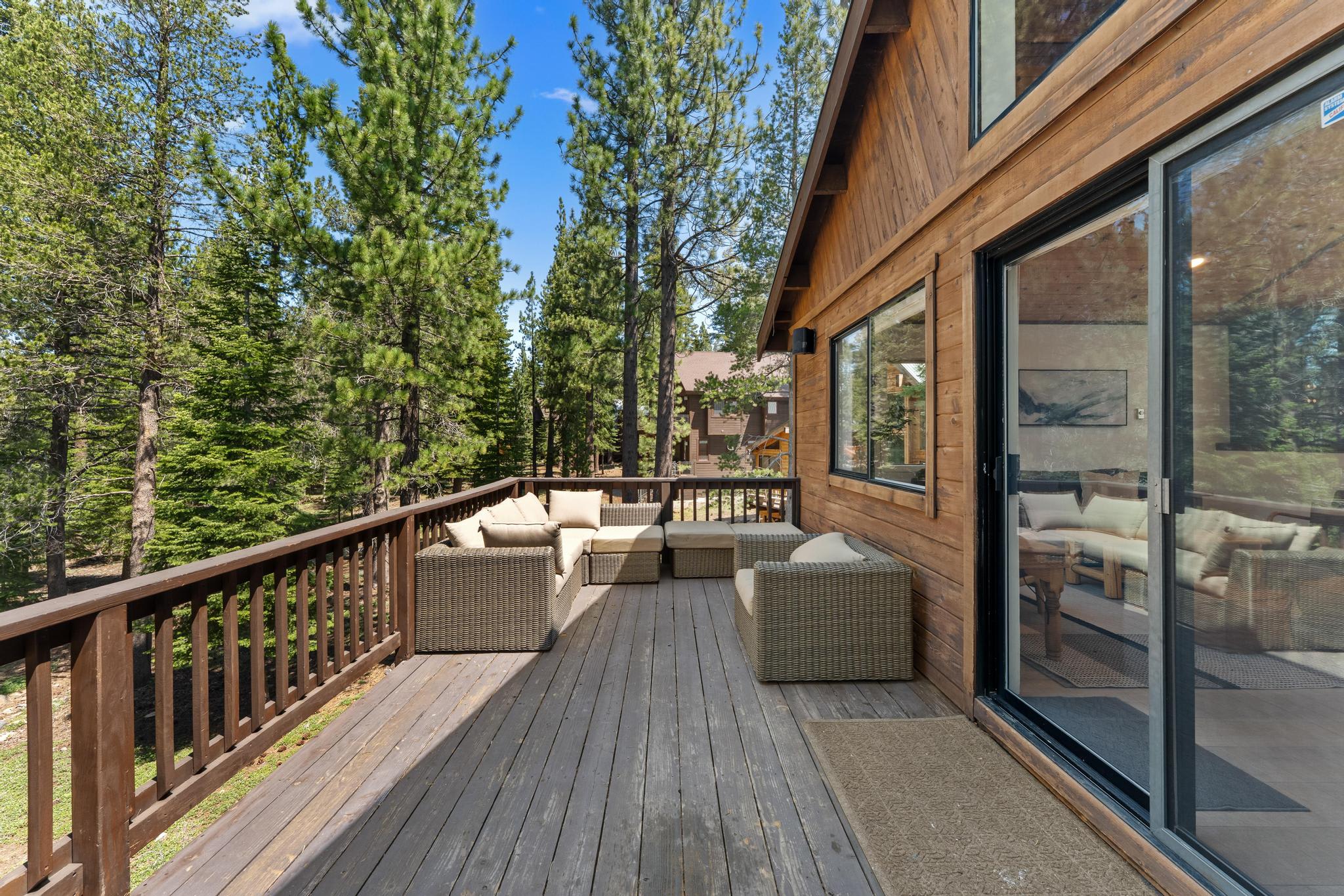Deck of a Truckee vacation rental with cozy outdoor seating surrounded by pine trees.