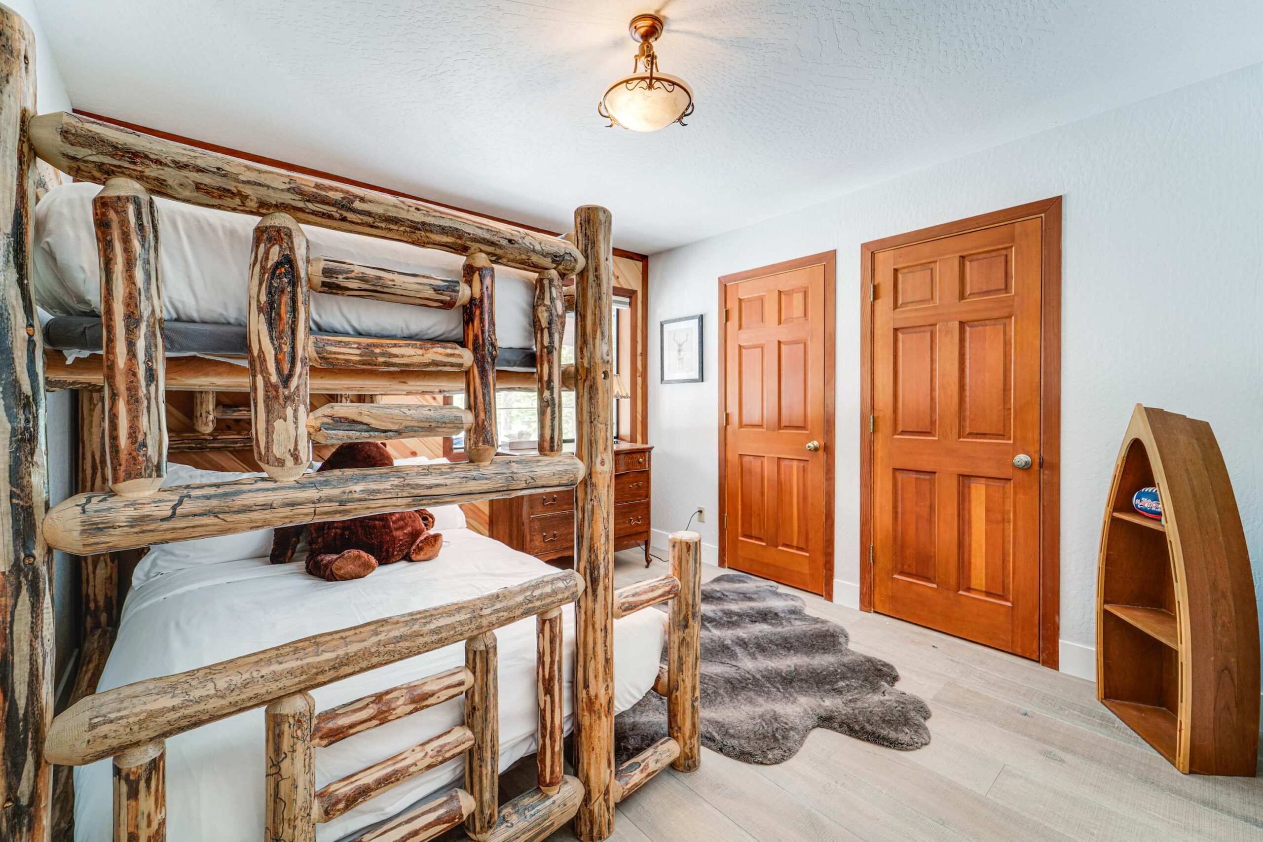 Rustic bunk bed room in a Truckee vacation rental with wooden decor, cozy rug, and dual closet doors.