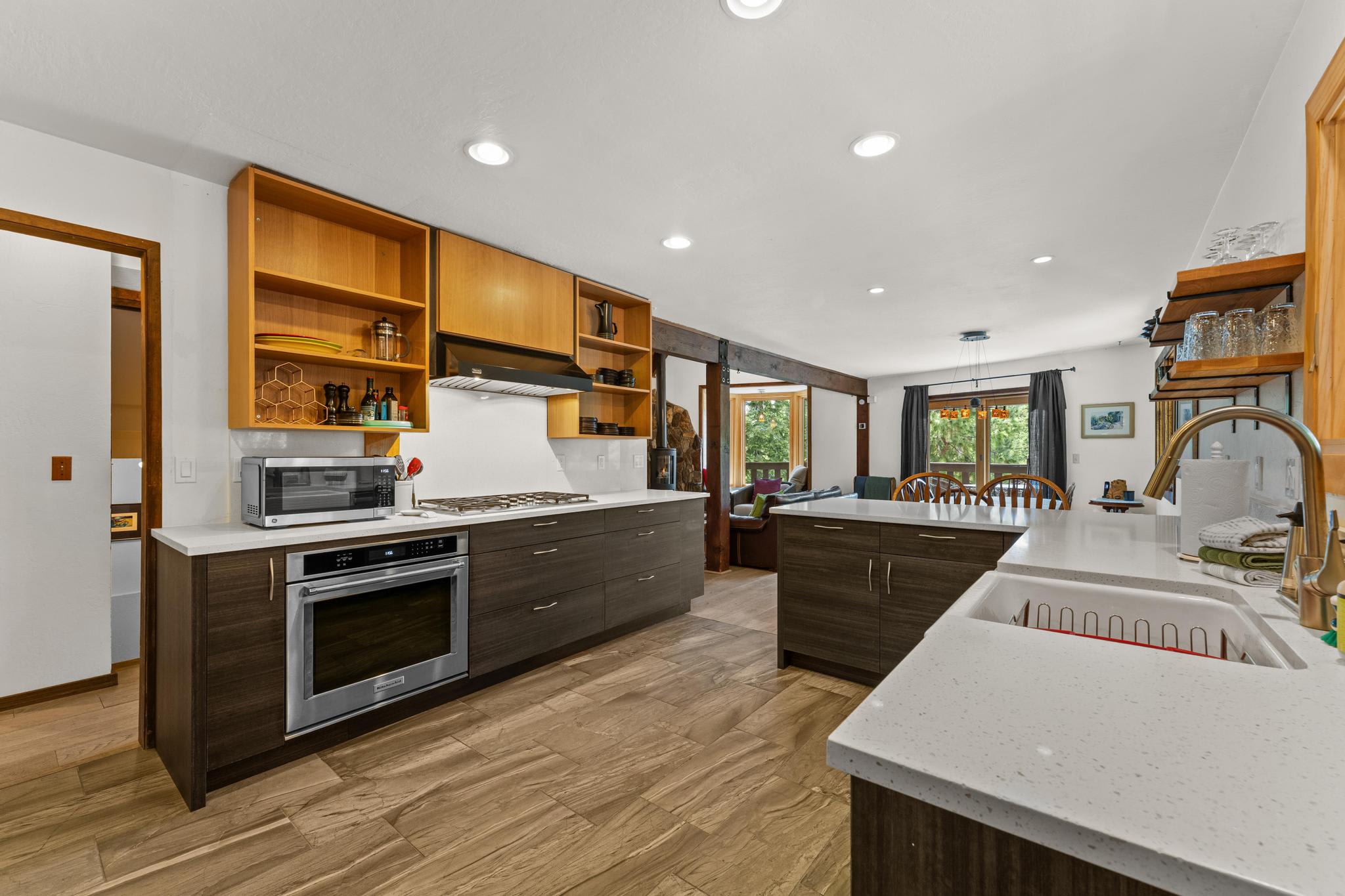 Modern kitchen in Tahoe Vista vacation rental, featuring sleek countertops, wooden cabinets, and dining space with large windows.
