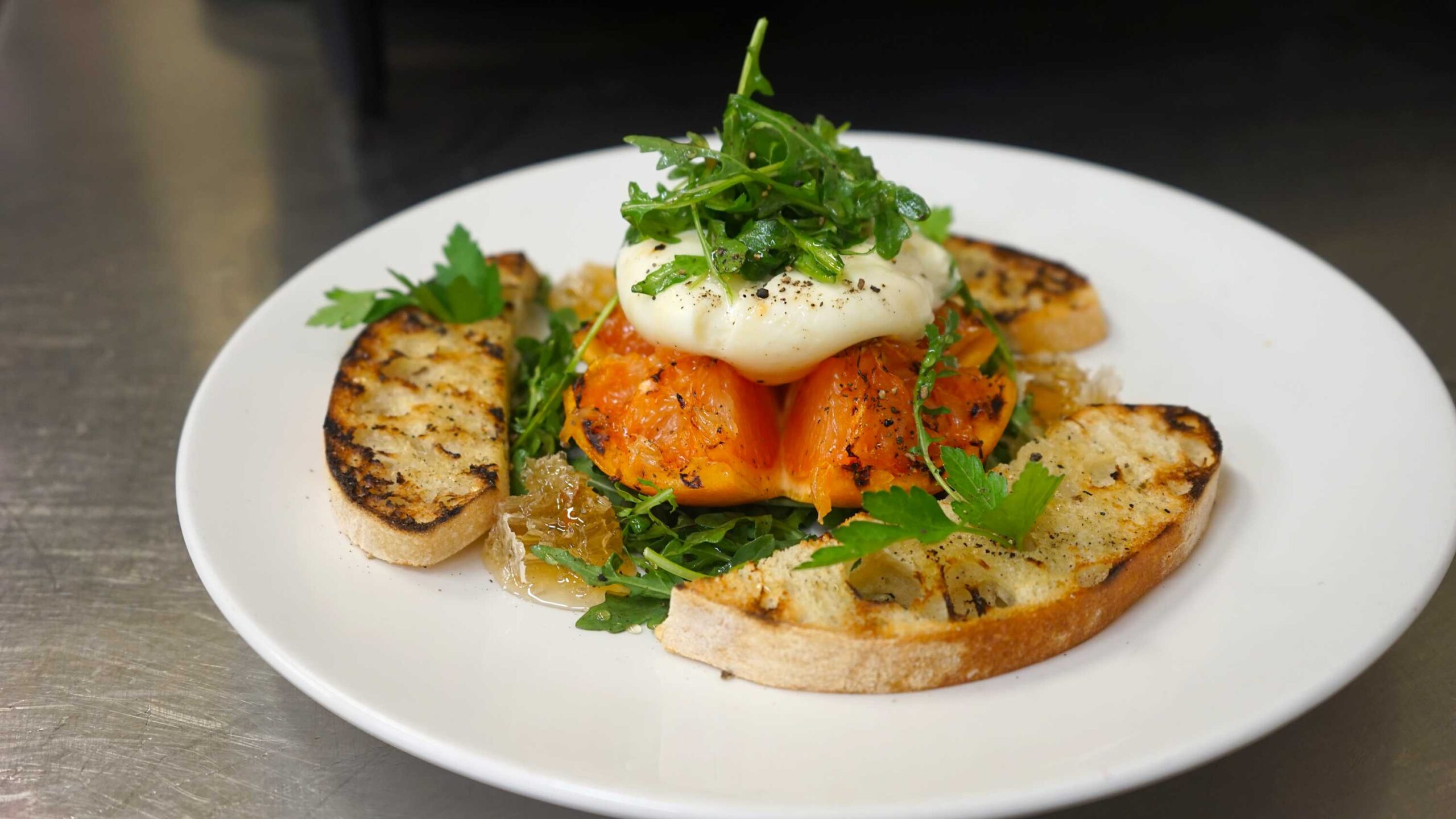 Gourmet dish with grilled bread and burrata at a Truckee vacation rental, served on a white plate.