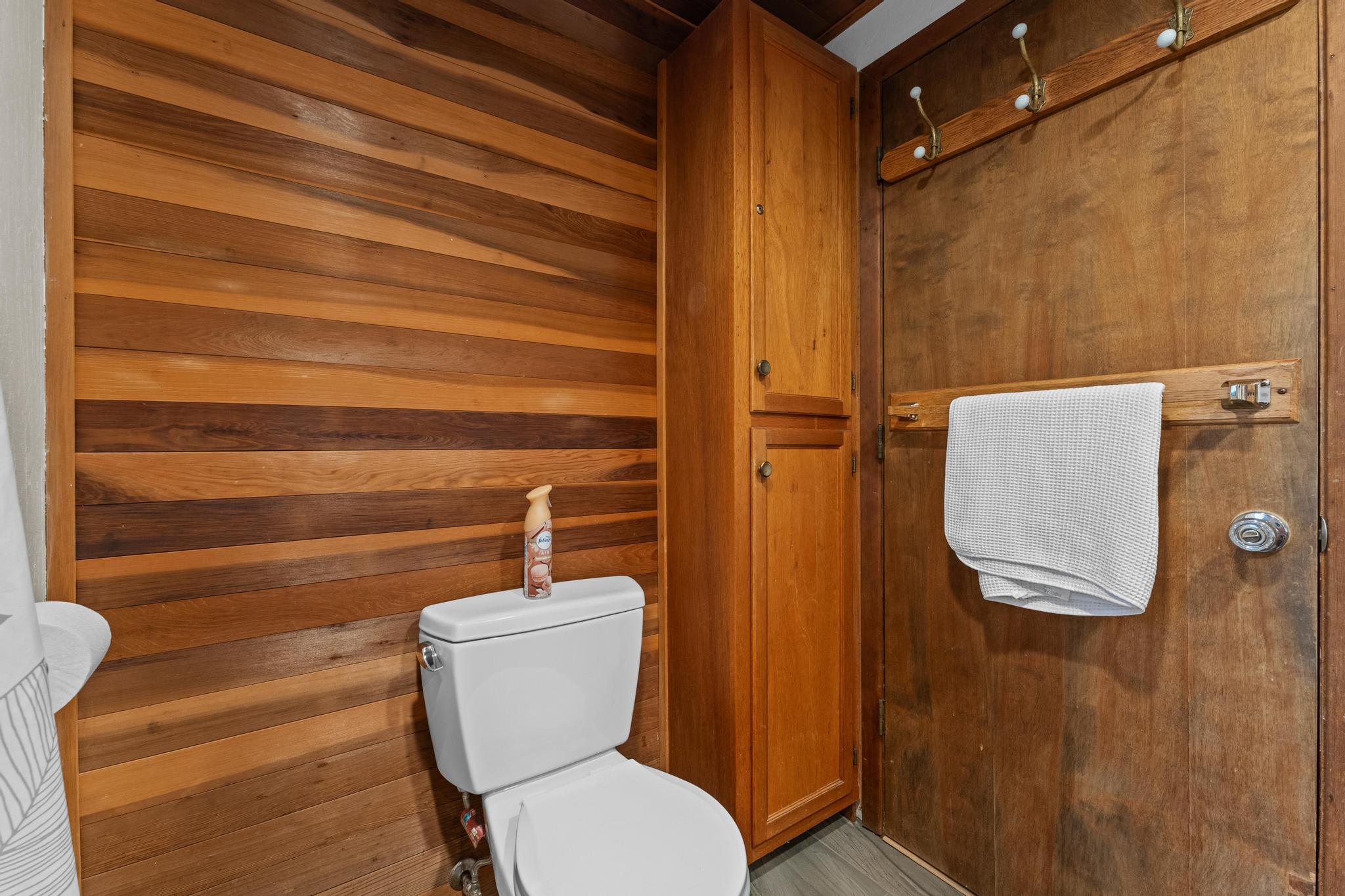 Bathroom in Tahoe Vista vacation rental with wood paneling, white towel, and toilet featuring an air freshener on top.