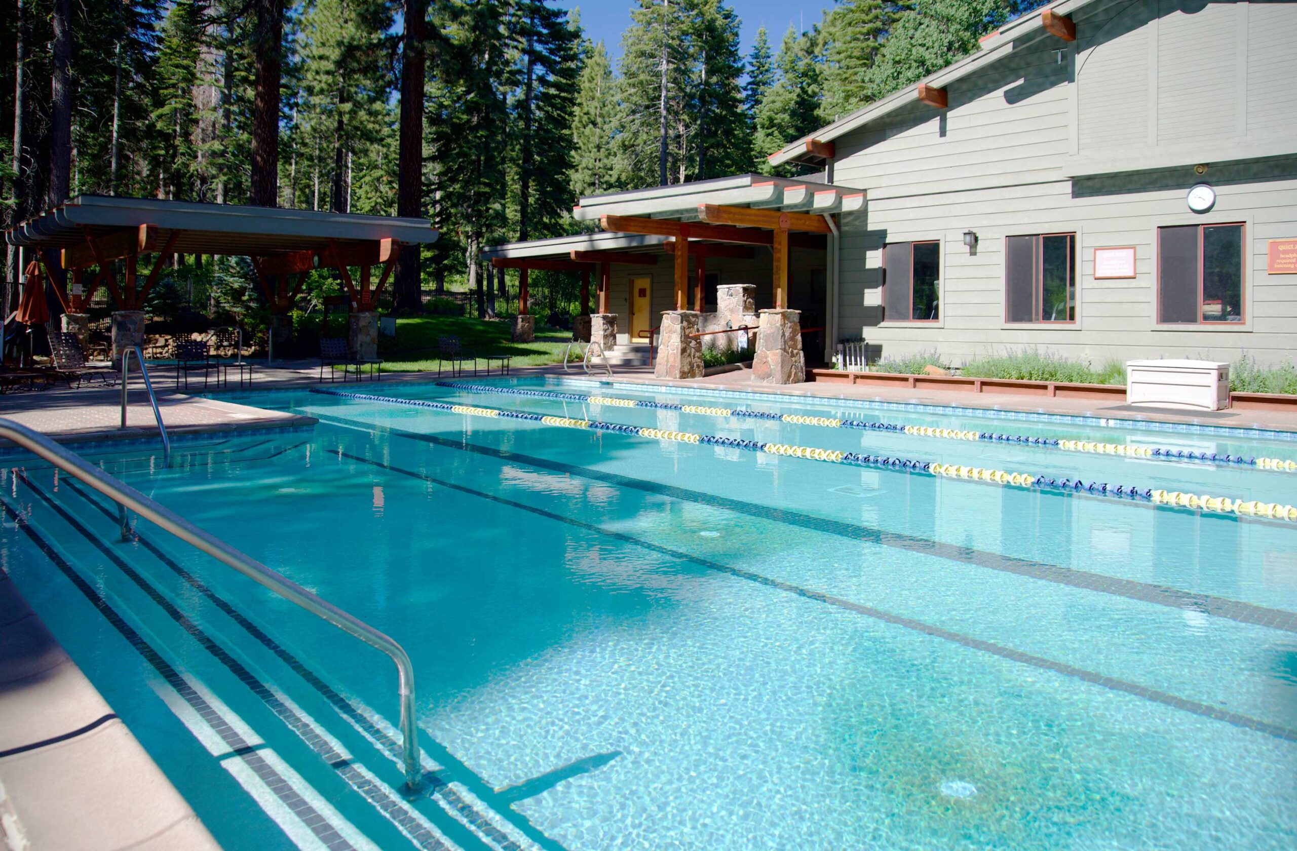 Outdoor swimming pool at a vacation rental in Truckee, surrounded by trees and a modern building.