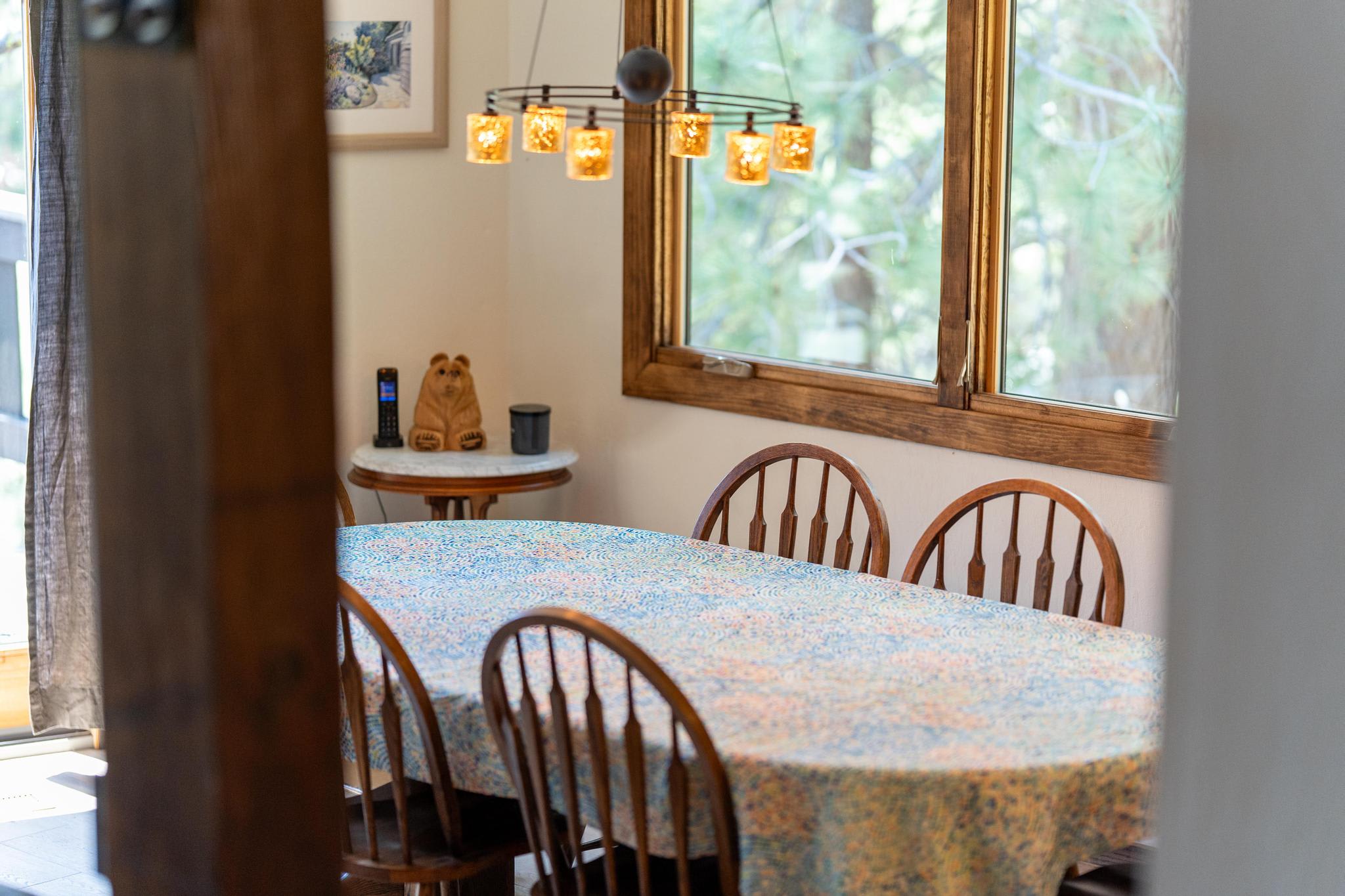 Dining area in a Tahoe Vista vacation rental with a table, chairs, and large window displaying forest views.