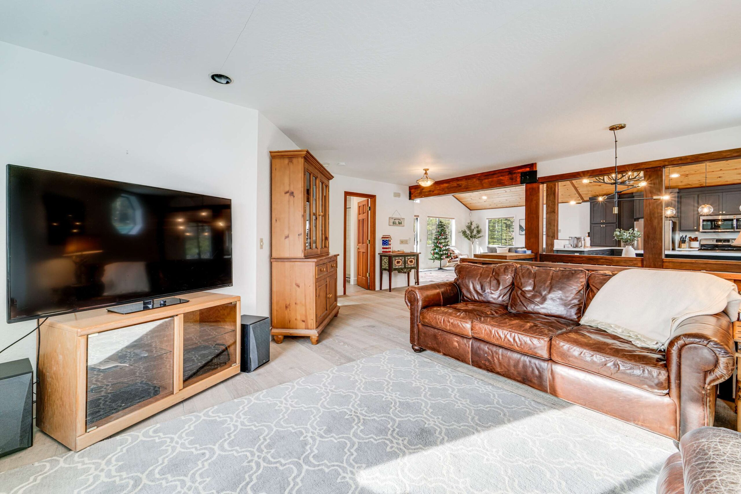 Cozy Truckee vacation rental living room with leather sofa, TV, and open kitchen. Bright and inviting space.